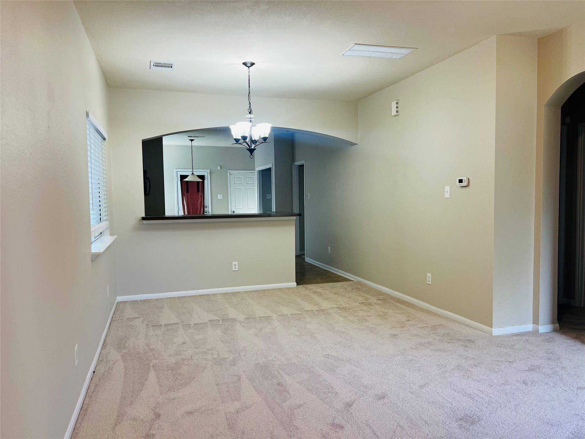 1721 Claremont Garden Circle, Houston, TX 77047 Spacious living area with plush carpet and neutral tones, featuring a modern light fixture and an open archway leading to the kitchen.