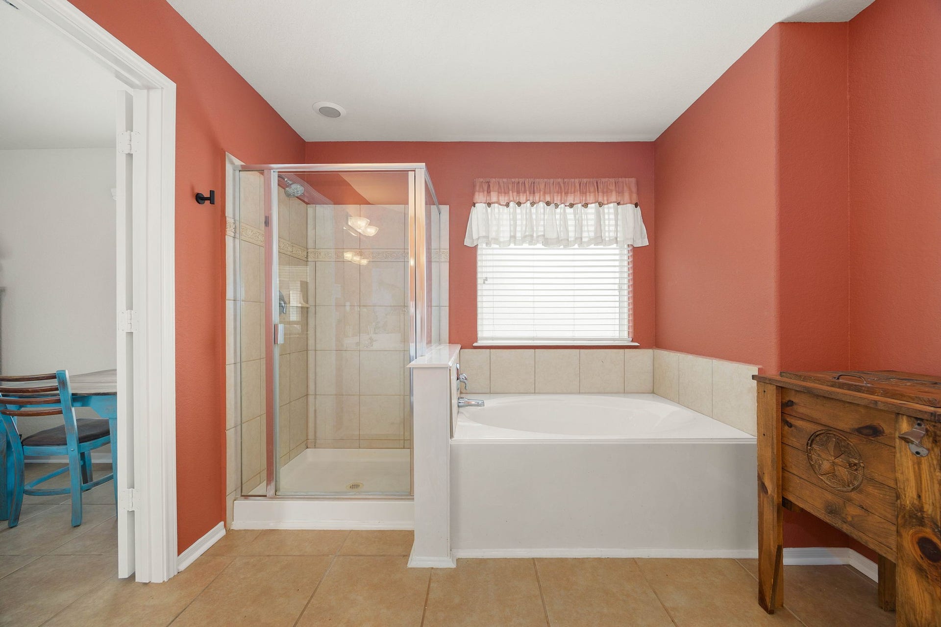 Relaxing primary en-suite bathroom featuring a dedicated setup with both a glass-enclosed walk-in shower and a separate, deep soaking tub. The space includes low-maintenance tile flooring, tile tub and shower surrounds, and a well-positioned window that provides natural light while maintaining privacy.