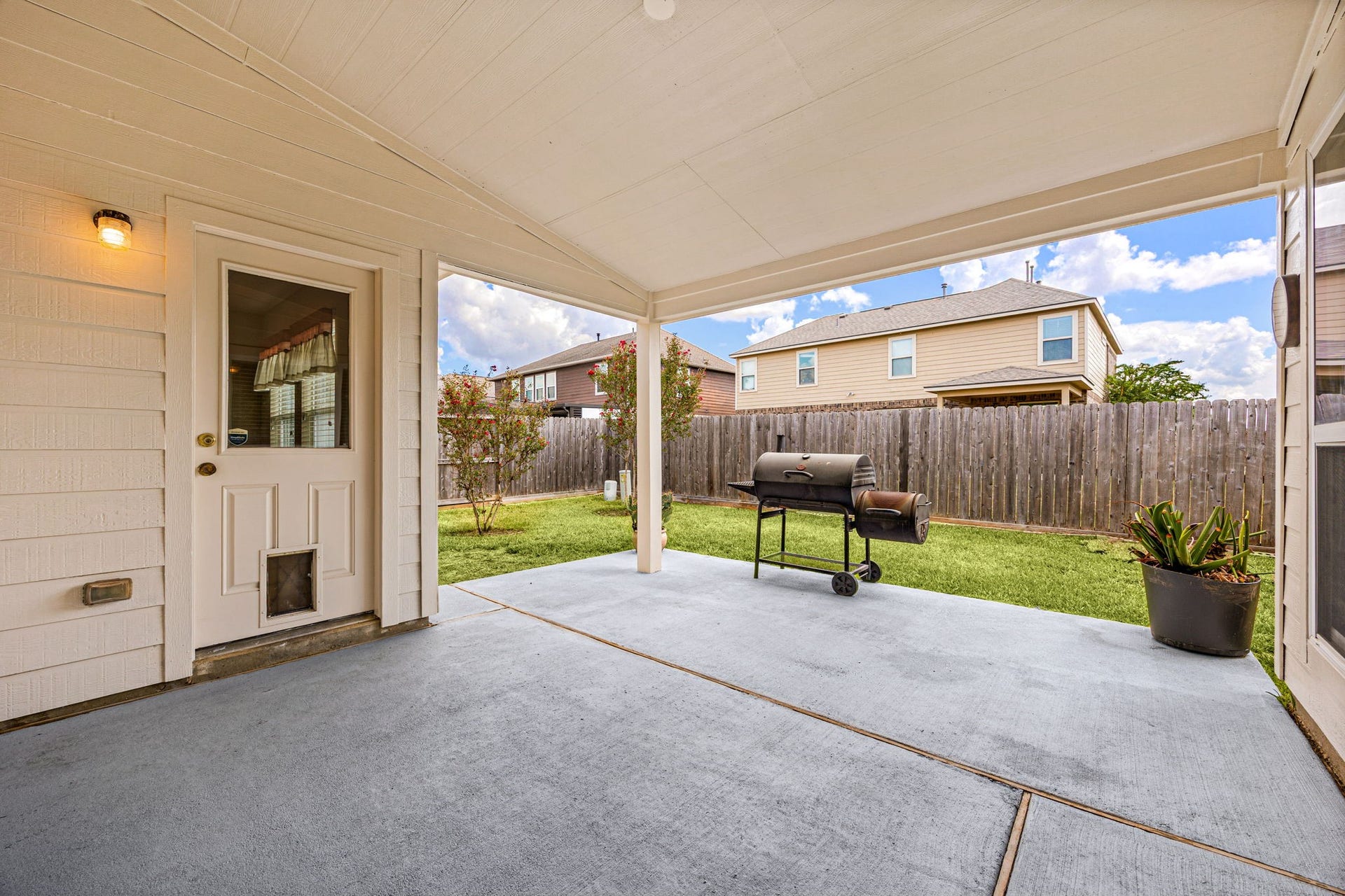 Inviting covered back patio featuring a durable concrete surface that opens up directly to a fully fenced backyard. This outdoor space provides the perfect layout for weekend barbecues or relaxing in the shade.