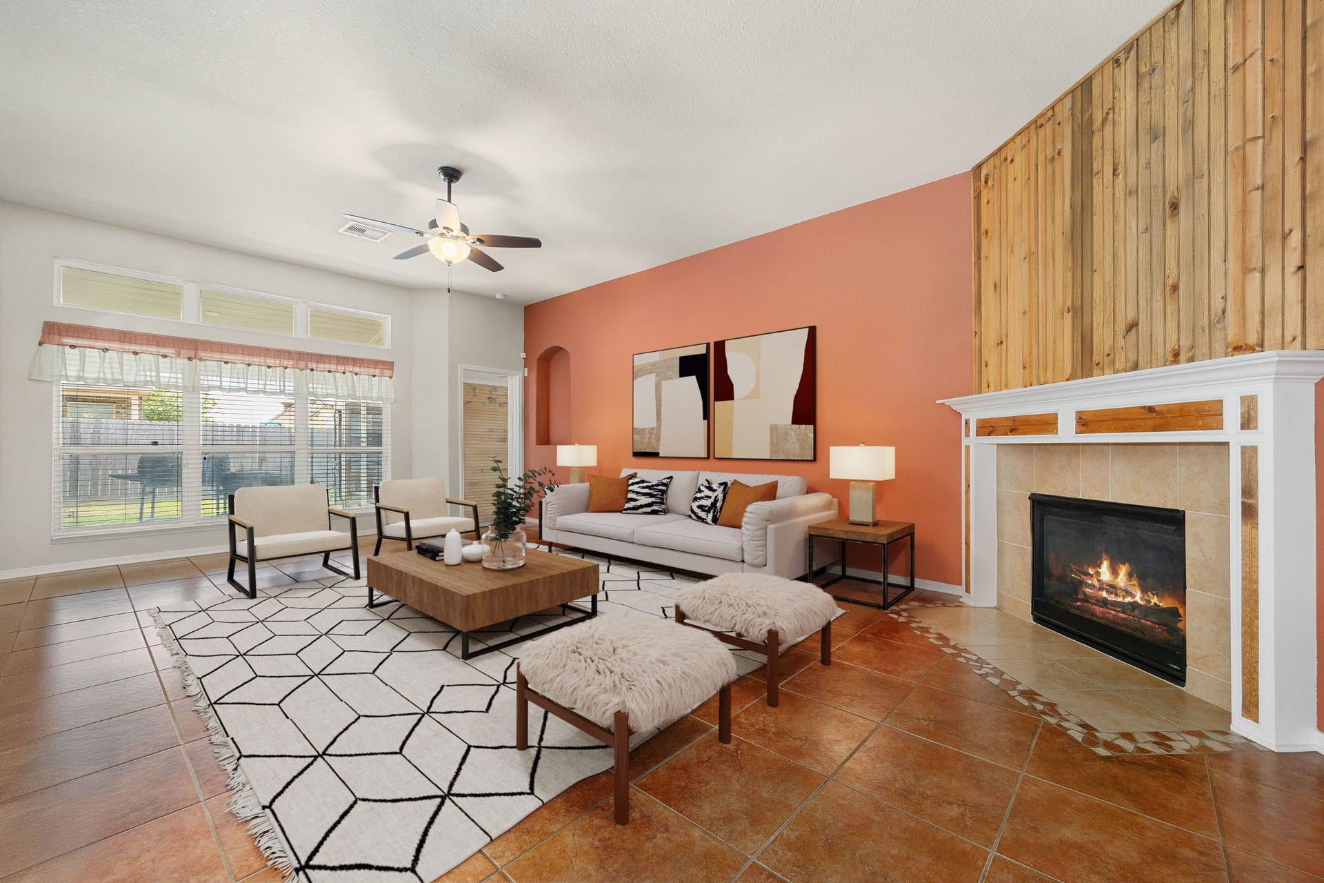Family room features a traditional wood-burning fireplace with a classic white mantle and neutral tile surround. The striking floor-to-ceiling wood plank accent wall highlights the soaring ceilings and creates a dramatic focal point for the space, while a bank of large windows offers comfortable backyard views and ample natural light. *Virtually Staged