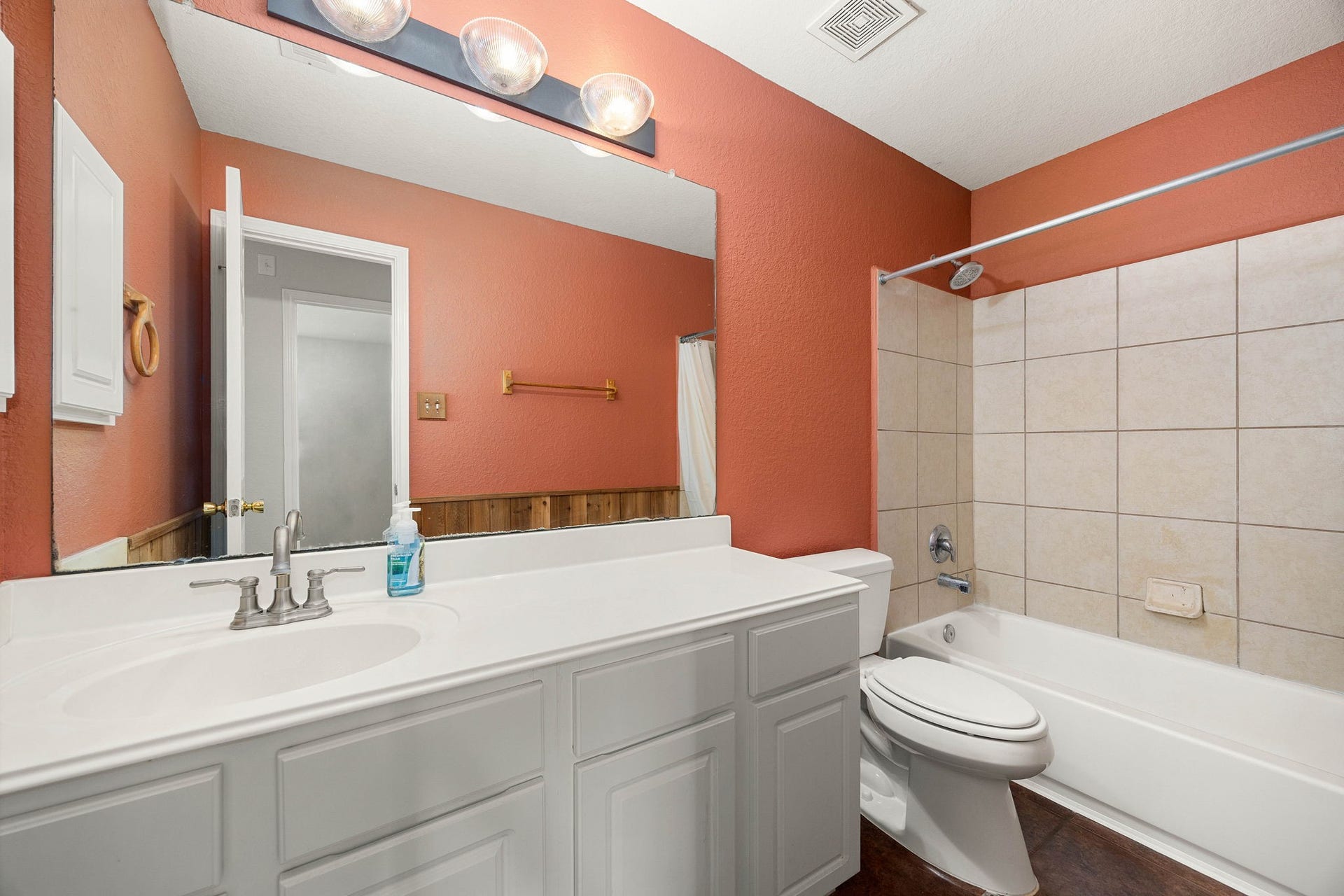 Functional and well-appointed secondary bathroom featuring an expansive vanity counter with generous space for everyday essentials. The tile-surround tub and shower combination maximizes usability, while a large vanity mirror helps keep the space open and well-lit.