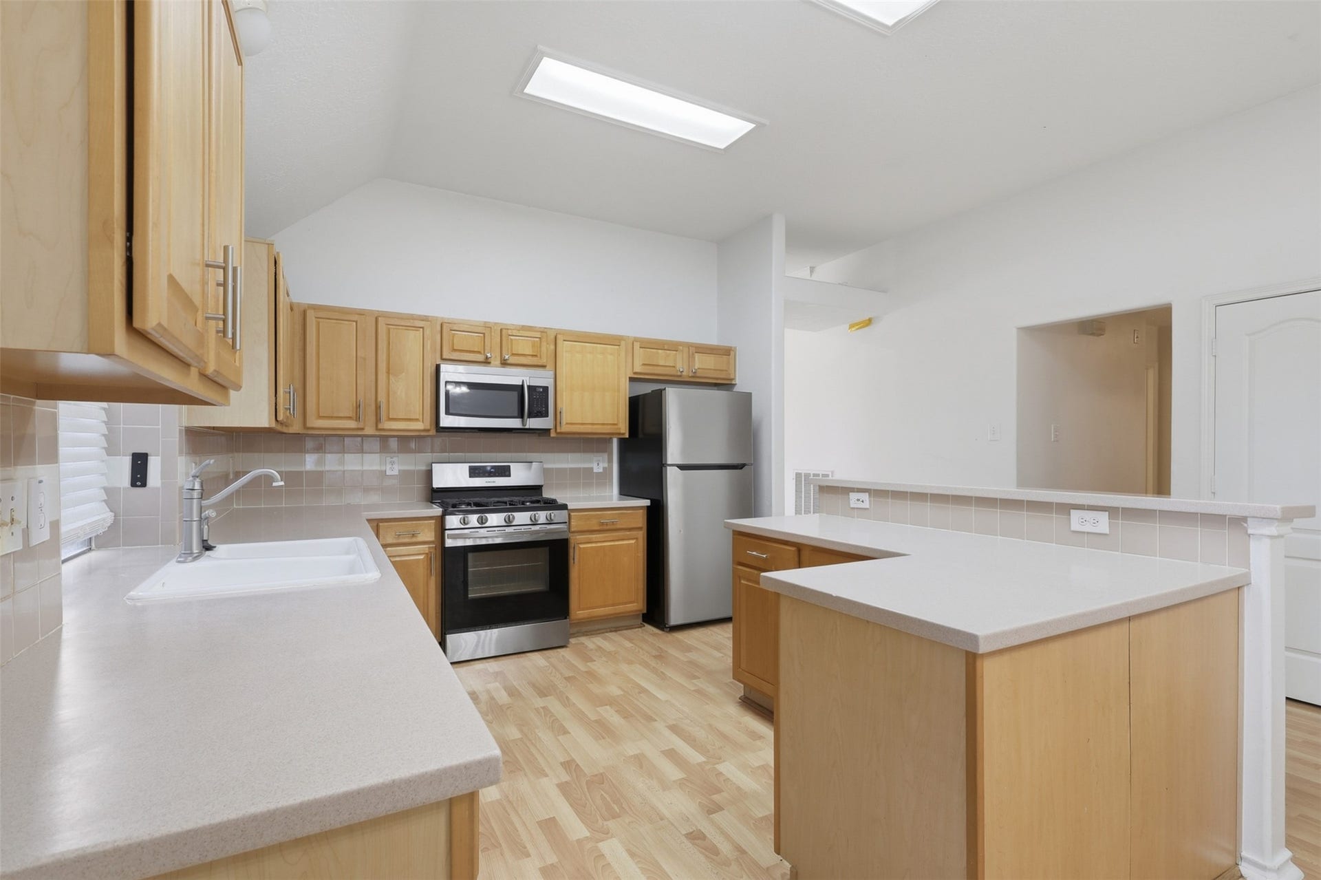 19319 Arbor Pines, Humble, TX 77346 Bright kitchen with natural wood cabinets, modern stainless steel appliances, and ample counter space. The open layout and neutral tones create a welcoming and functional area for cooking and entertaining.