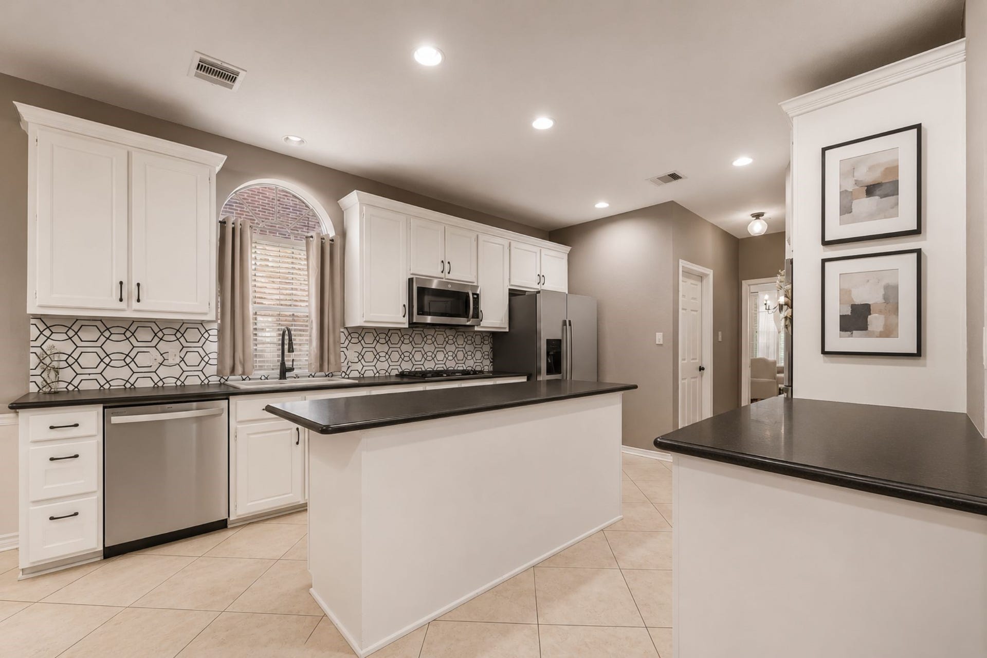UPDATED KITCHEN FEATURES A GEOMETRIC TILE BACKSPLASH, STAINLESS STEEL APPLIANCES AND A PLETHORA OF COUNTER SPACE - PERFECT FOR PREPPING DELICIOUS MEALS!