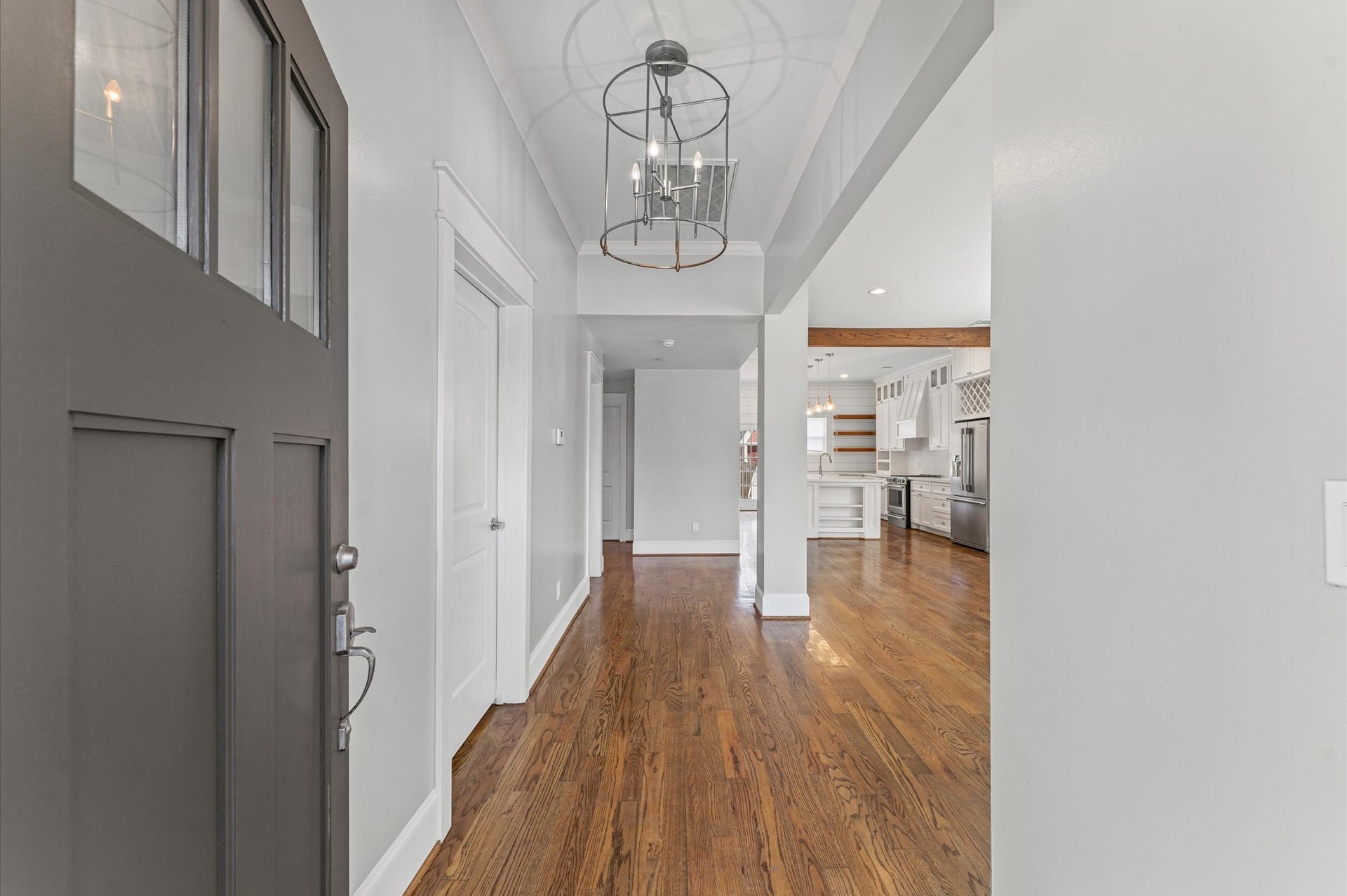 1204 Shearn Street, Houston, TX 77007 This photo showcases a bright entryway with hardwood floors, leading into an open-concept kitchen. The space features modern lighting, white cabinetry, and stainless steel appliances, creating a welcoming and contemporary feel.