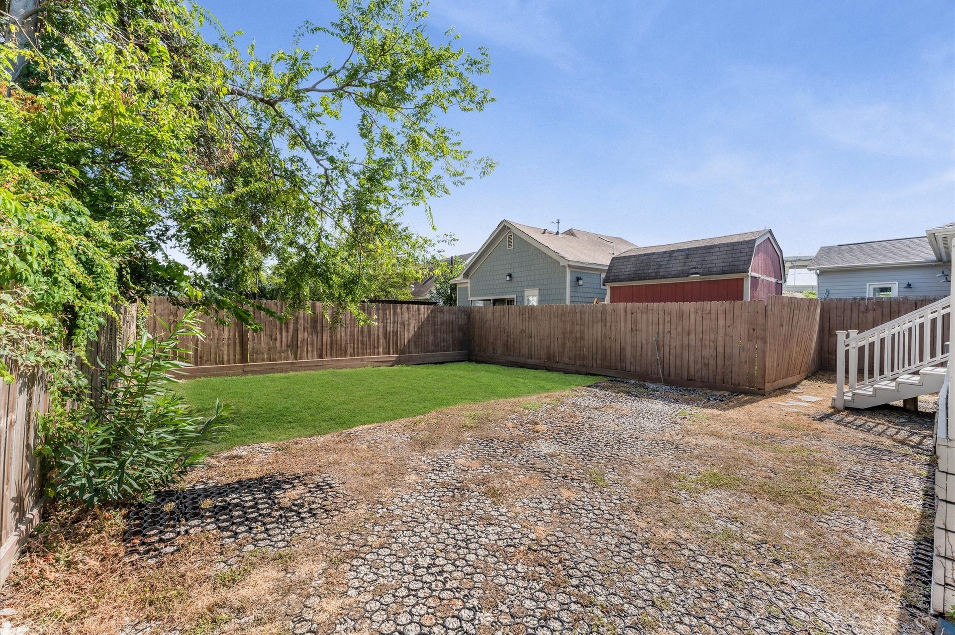1204 Shearn Street, Houston, TX 77007 This backyard features a mix of green lawn and gravel area, enclosed by a wooden fence. It offers a spacious outdoor area with a small tree for shade and a storage shed in the back. Perfect for gardening or entertaining.