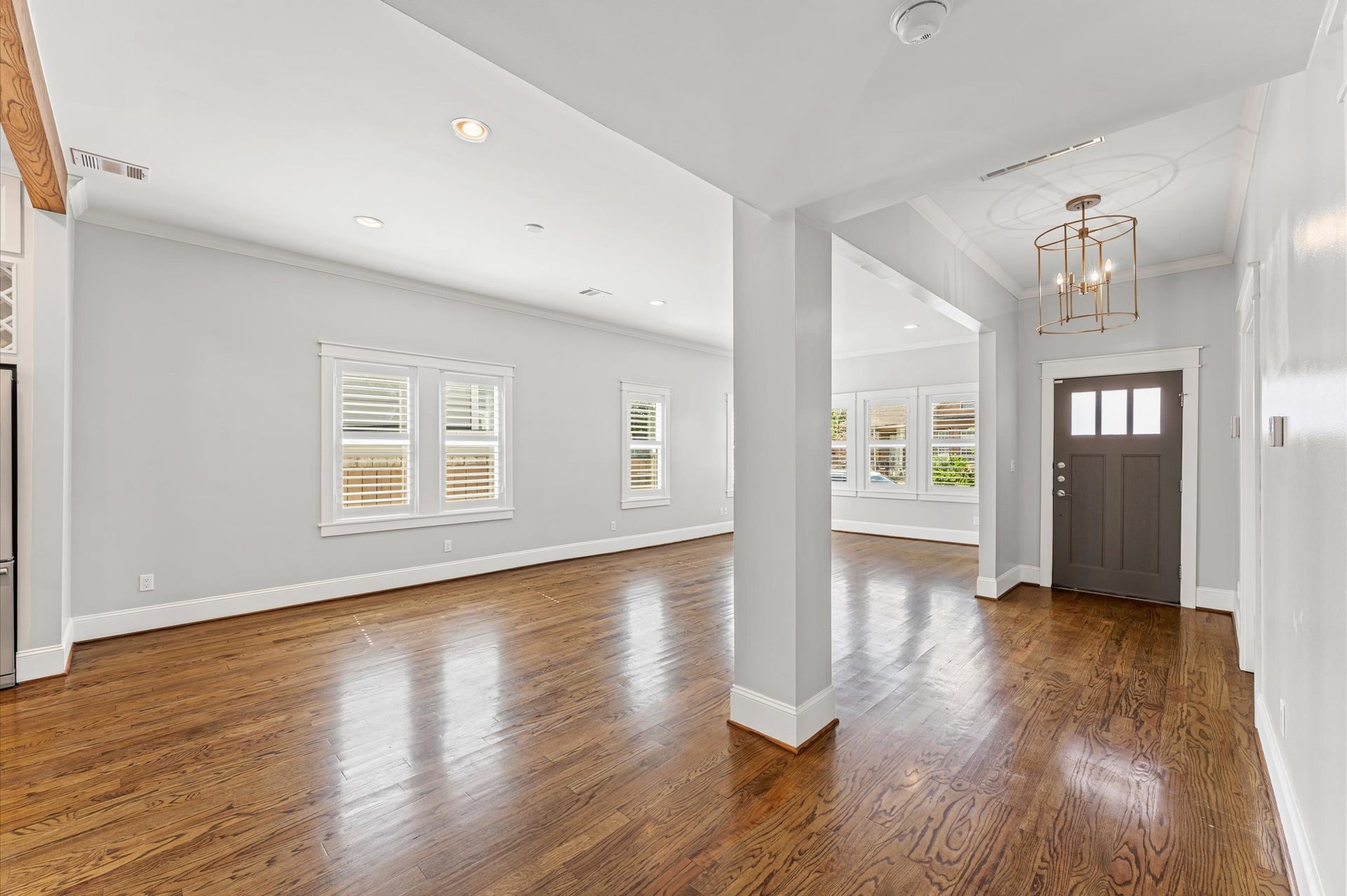 1204 Shearn Street, Houston, TX 77007 Bright and spacious open-concept living area with hardwood floors, large windows, and a modern light fixture. Features a welcoming entryway with a stylish front door.