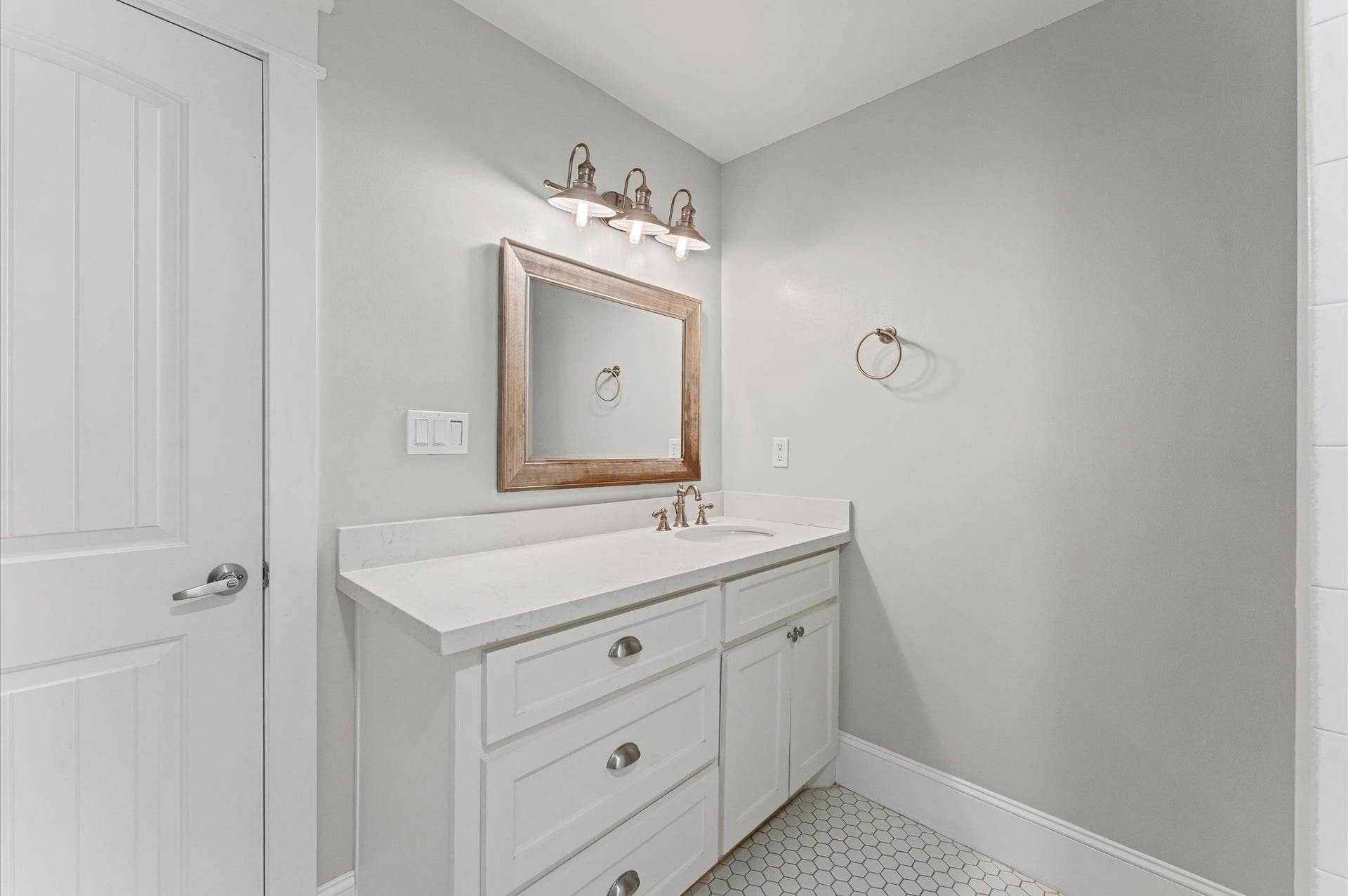 1204 Shearn Street, Houston, TX 77007 This bathroom features a modern design with a light gray color scheme, a white vanity with ample storage, and a stylish wooden-framed mirror. The space is well-lit with elegant overhead lighting and has a sleek, clean look.