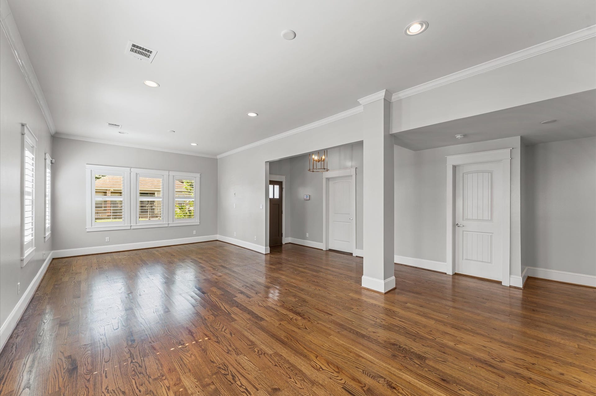 1204 Shearn Street, Houston, TX 77007 Spacious, bright living area with hardwood floors, neutral walls, and recessed lighting. Features large windows, elegant trim, and a modern light fixture near the entrance. Ideal for versatile living arrangements.