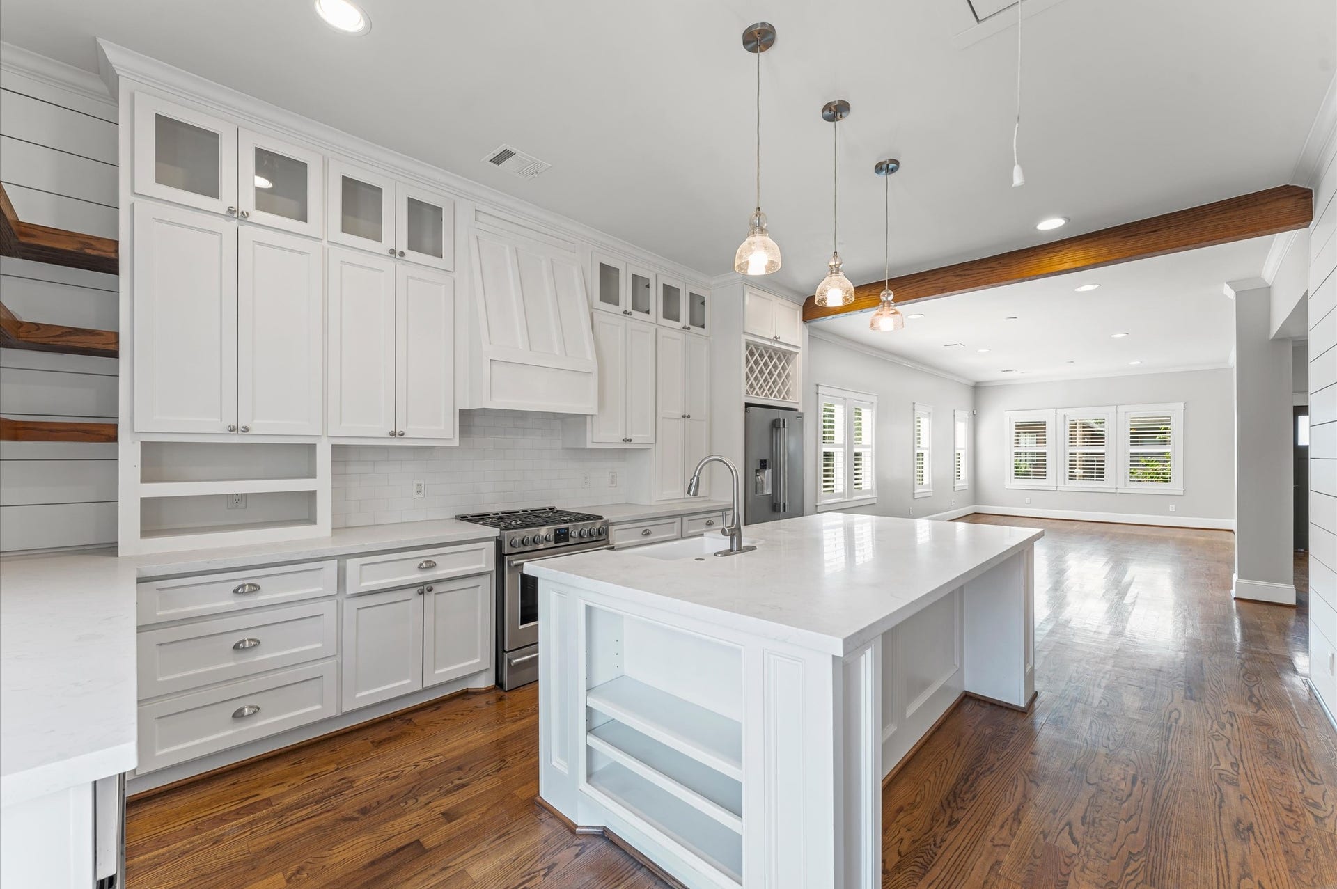 1204 Shearn Street, Houston, TX 77007 This spacious, modern kitchen features sleek white cabinetry, a large island with a sink, and stainless steel appliances. Hardwood floors and ample natural light create a warm, inviting atmosphere. Ideal for entertaining and family gatherings.