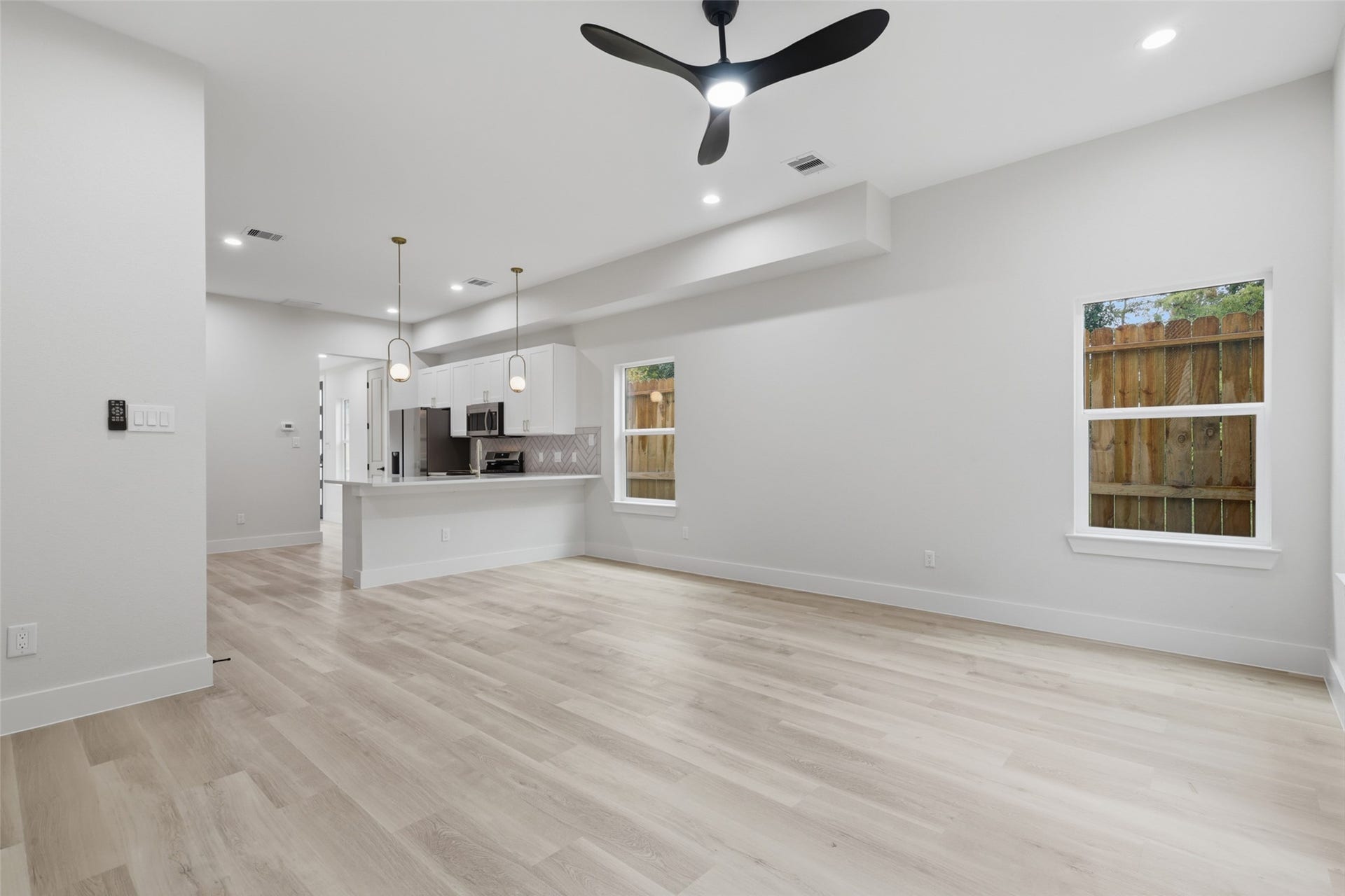 3201 Berry Street, #A/B, Houston, TX 77004 Spacious open-concept living area with sleek LVP flooring, modern ceiling fan, and abundant natural light, seamlessly flowing into a contemporary kitchen with stylish pendant lighting and stainless steel appliances.
