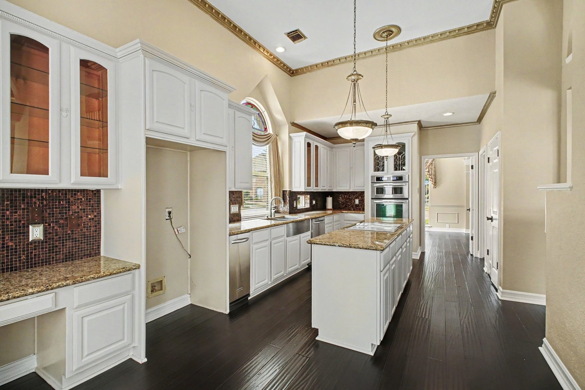 5406 Brook Bend Drive, Sugar Land, TX 77479 This lovely kitchen features elegant pendant lighting, decorative cornice and glass-paneled cabinets