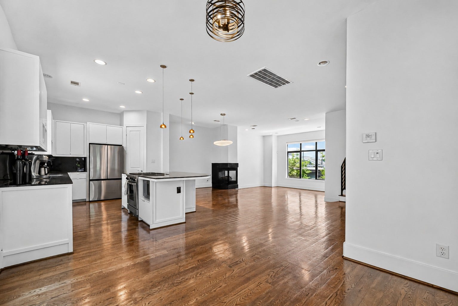 1110 Autrey Street, #C, Houston, TX 77006 Spacious open-concept living area with gleaming hardwood floors, a modern kitchen featuring stainless steel appliances, and a cozy fireplace. Large windows provide abundant natural light and scenic views.