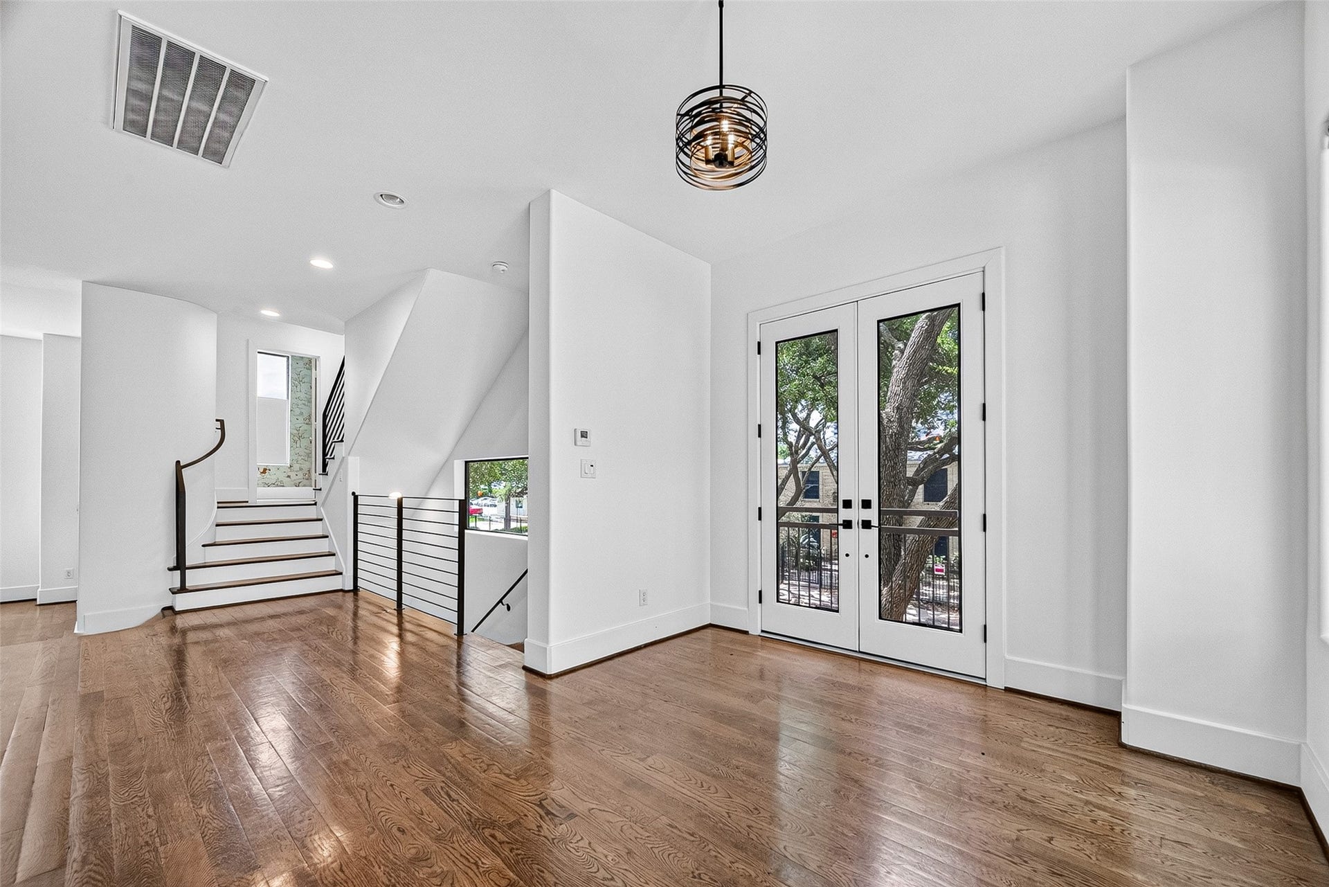 1110 Autrey Street, #C, Houston, TX 77006 Bright and inviting breakfast area with elegant hardwood floors, modern lighting, and glass double doors leading to a patio. A sleek staircase enhances the contemporary design.