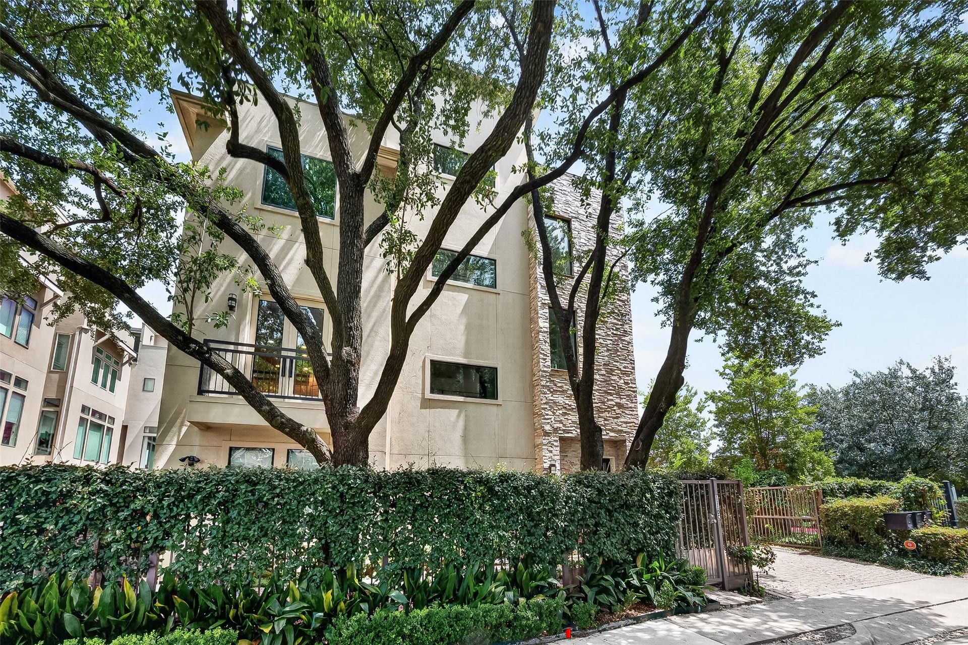 1110 Autrey Street, #C, Houston, TX 77006 Contemporary multi-story home nestled among mature trees, featuring a blend of stone and stucco exterior with lush landscaping for added privacy.