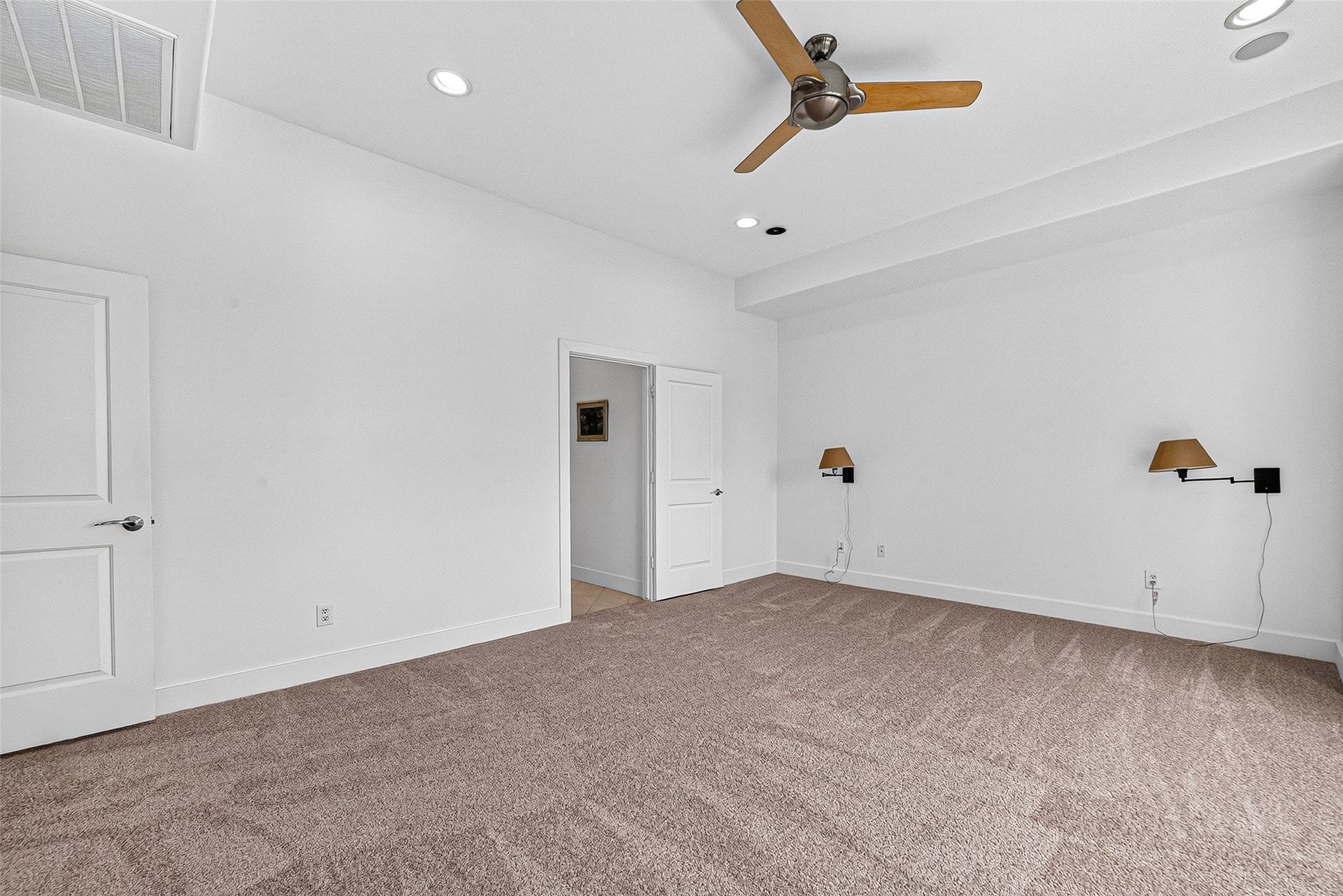 1110 Autrey Street, #C, Houston, TX 77006 Spacious primary bedroom with plush carpeting, recessed lighting, and a stylish ceiling fan, offering a clean, modern design perfect for relaxation.