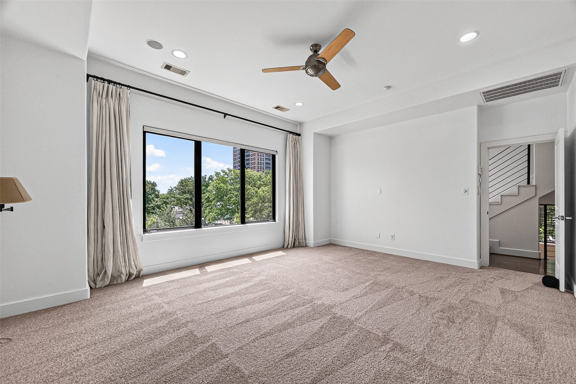 1110 Autrey Street, #C, Houston, TX 77006 Spacious primary bedroom with plush carpeting, large window offering lush views, and a stylish ceiling fan.