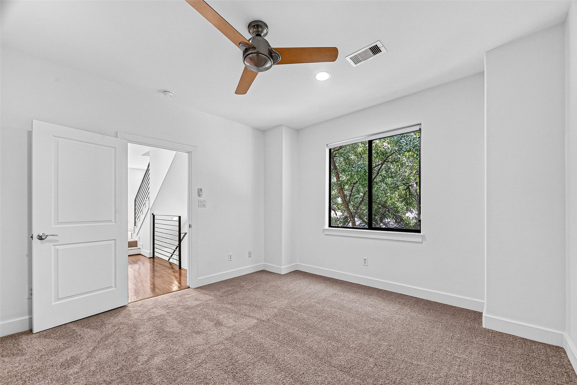 1110 Autrey Street, #C, Houston, TX 77006 Spacious bedroom on third floor with plush carpeting, features a large window offering views of lush greenery and ample natural light.