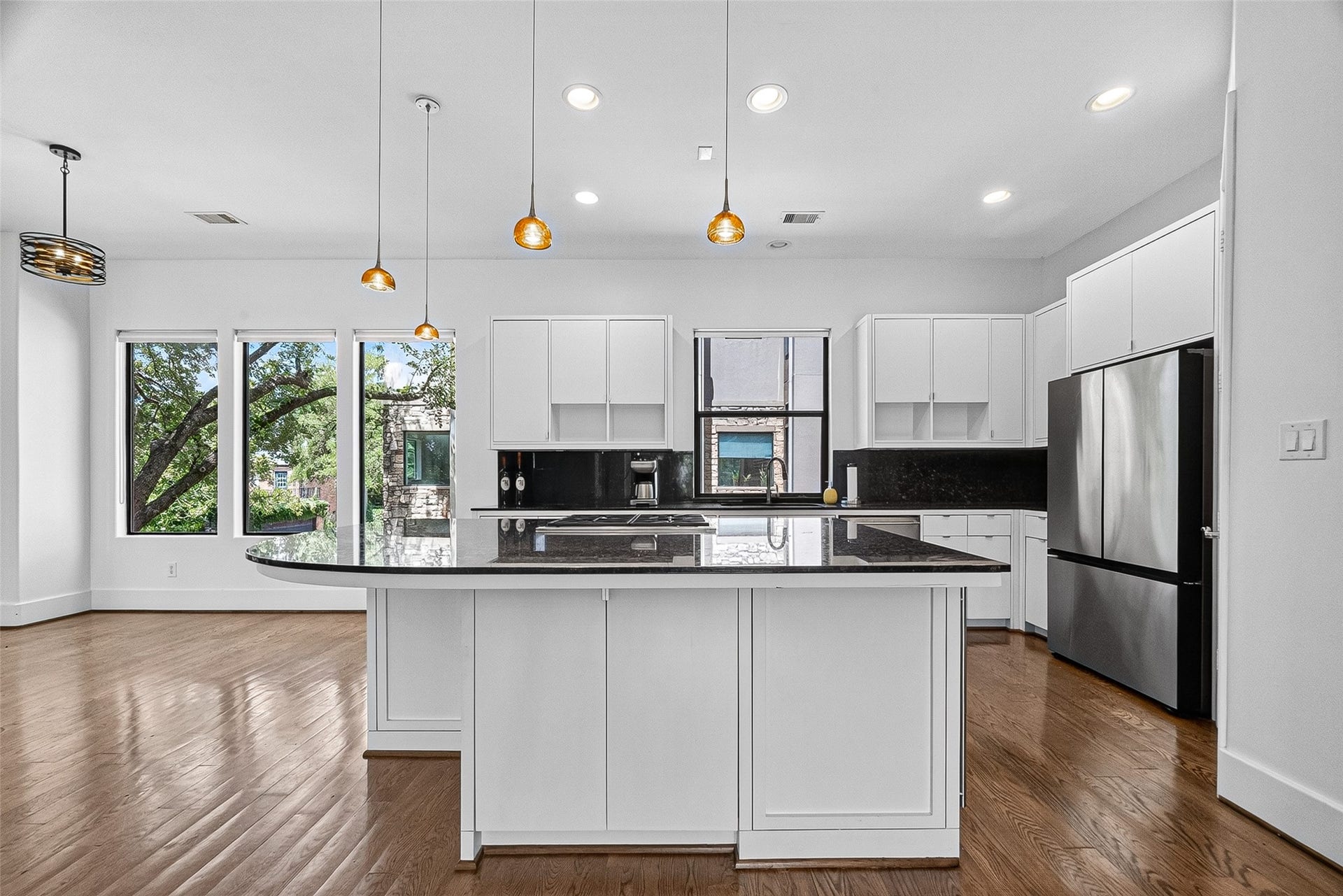 1110 Autrey Street, #C, Houston, TX 77006 Bright and modern kitchen featuring sleek white cabinetry, a large center island with dark countertops, stainless steel appliances, and ample natural light from expansive windows.
