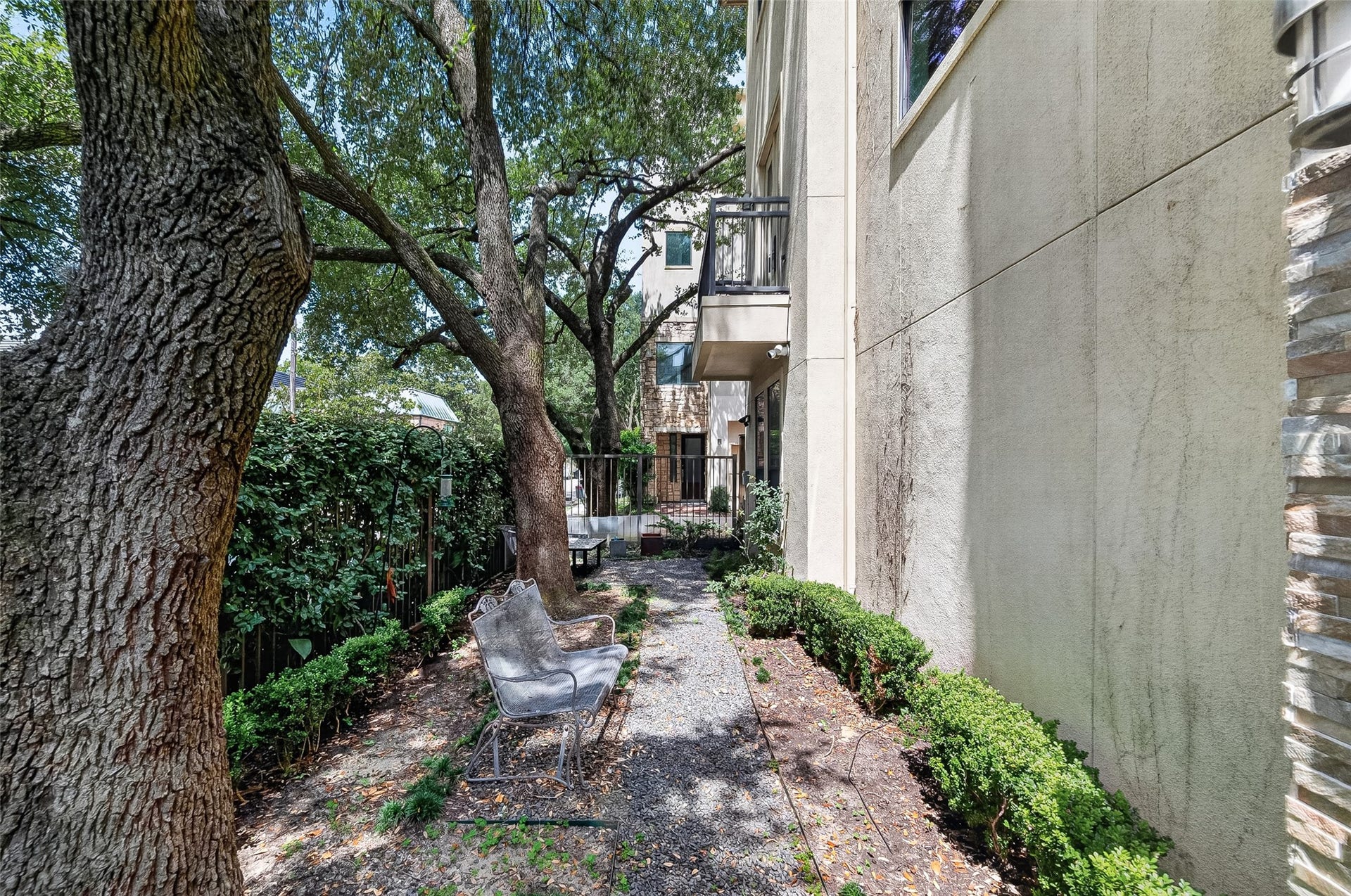 1110 Autrey Street, #C, Houston, TX 77006 Charming outdoor space with mature trees providing shade, a cozy seating area, and a pathway lined with lush greenery, perfect for relaxation and privacy.