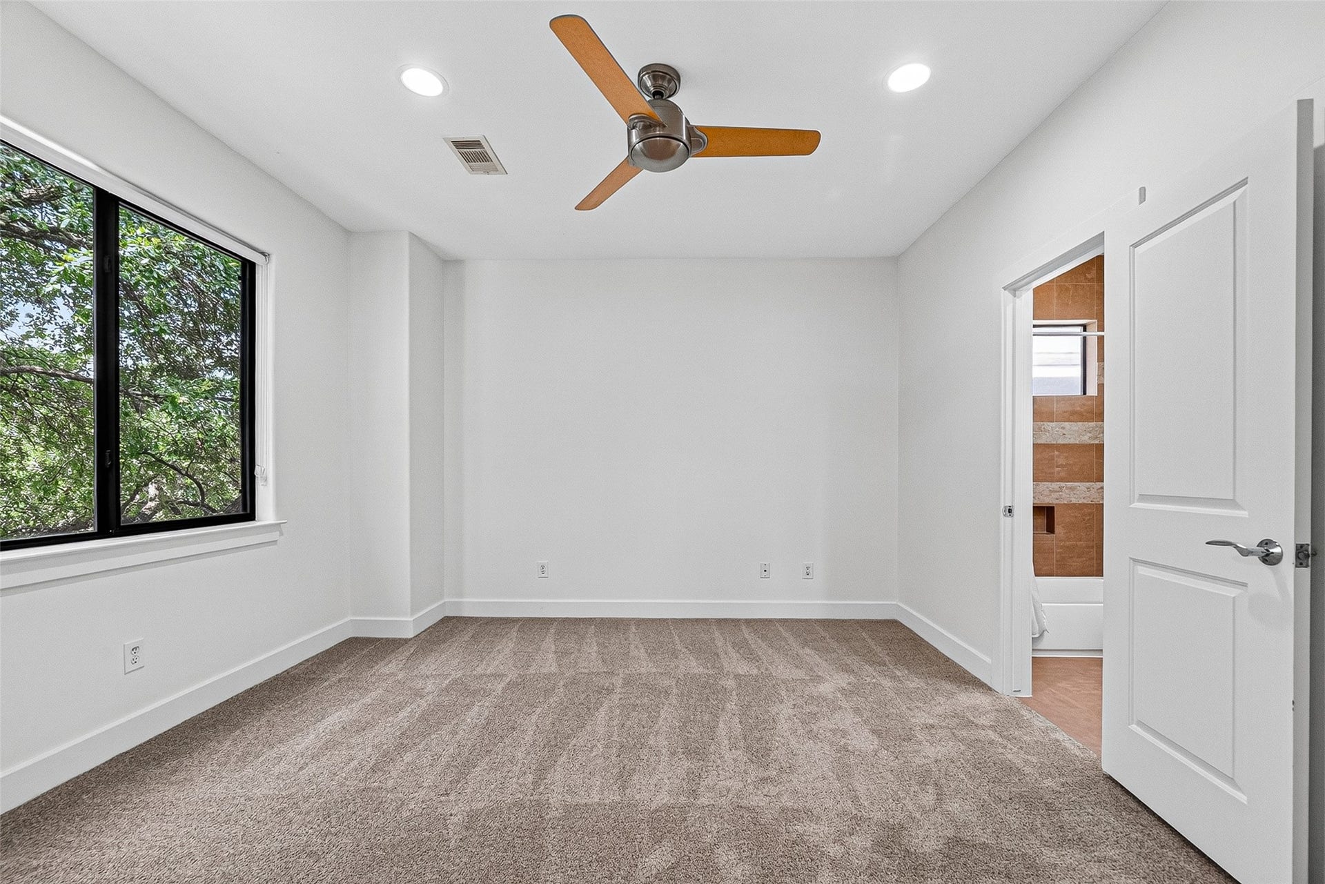 1110 Autrey Street, #C, Houston, TX 77006 Spacious bedroom on second floor with plush carpeting, a modern ceiling fan, and large window providing natural light. Similar bedroom also on the first floor with en-suite bathroom.