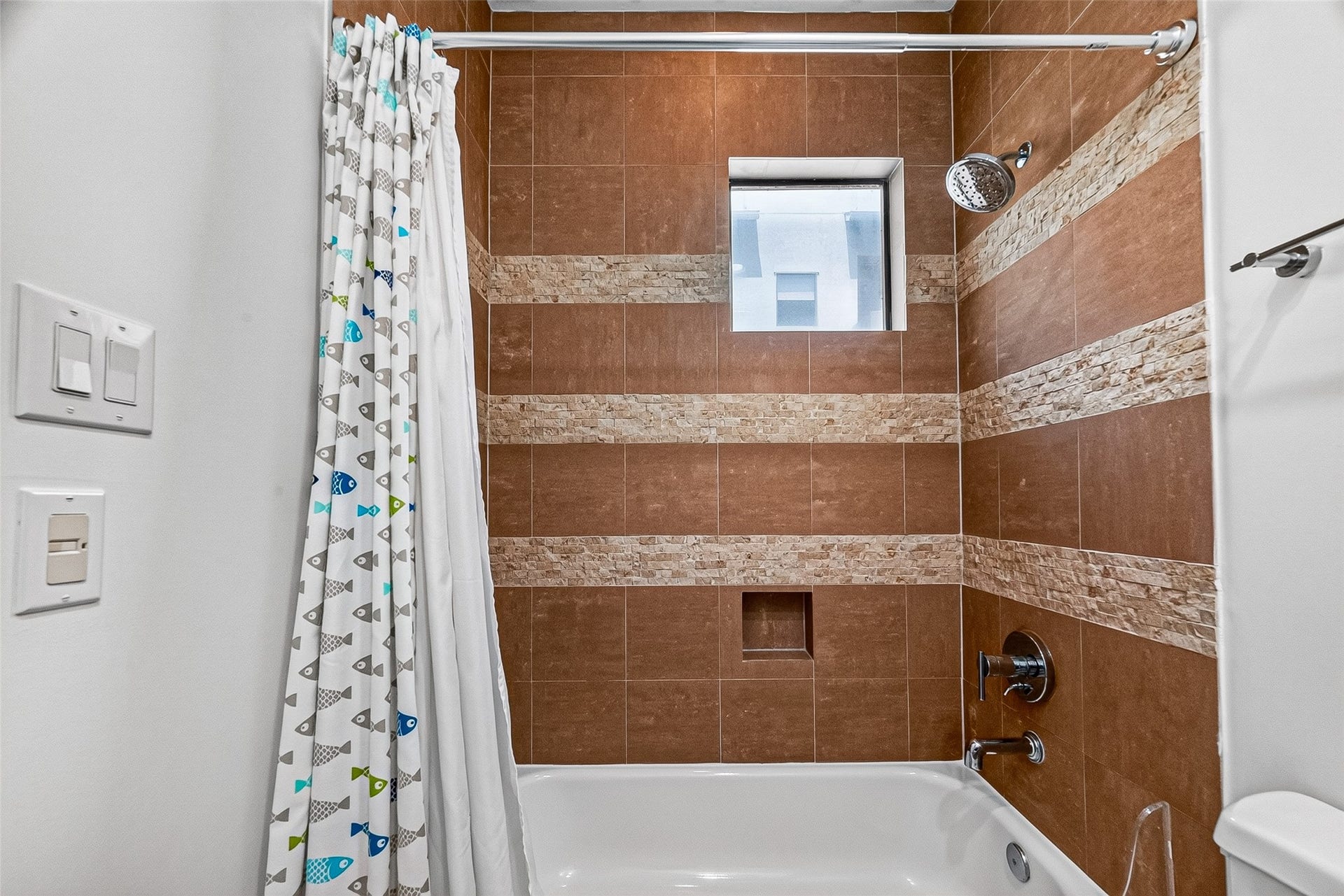1110 Autrey Street, #C, Houston, TX 77006 Charming bathroom in bedroom on third floor with elegant brown tilework featuring decorative stone accents, and a modern showerhead.