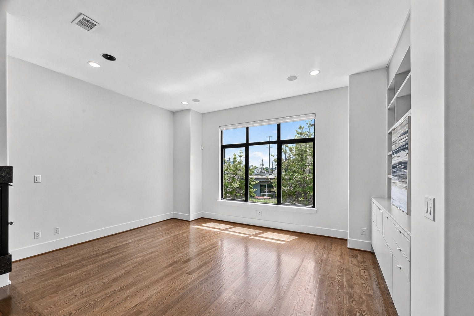 1110 Autrey Street, #C, Houston, TX 77006 Bright and spacious living room with large windows, sleek built-in shelving, and elegant hardwood floors.