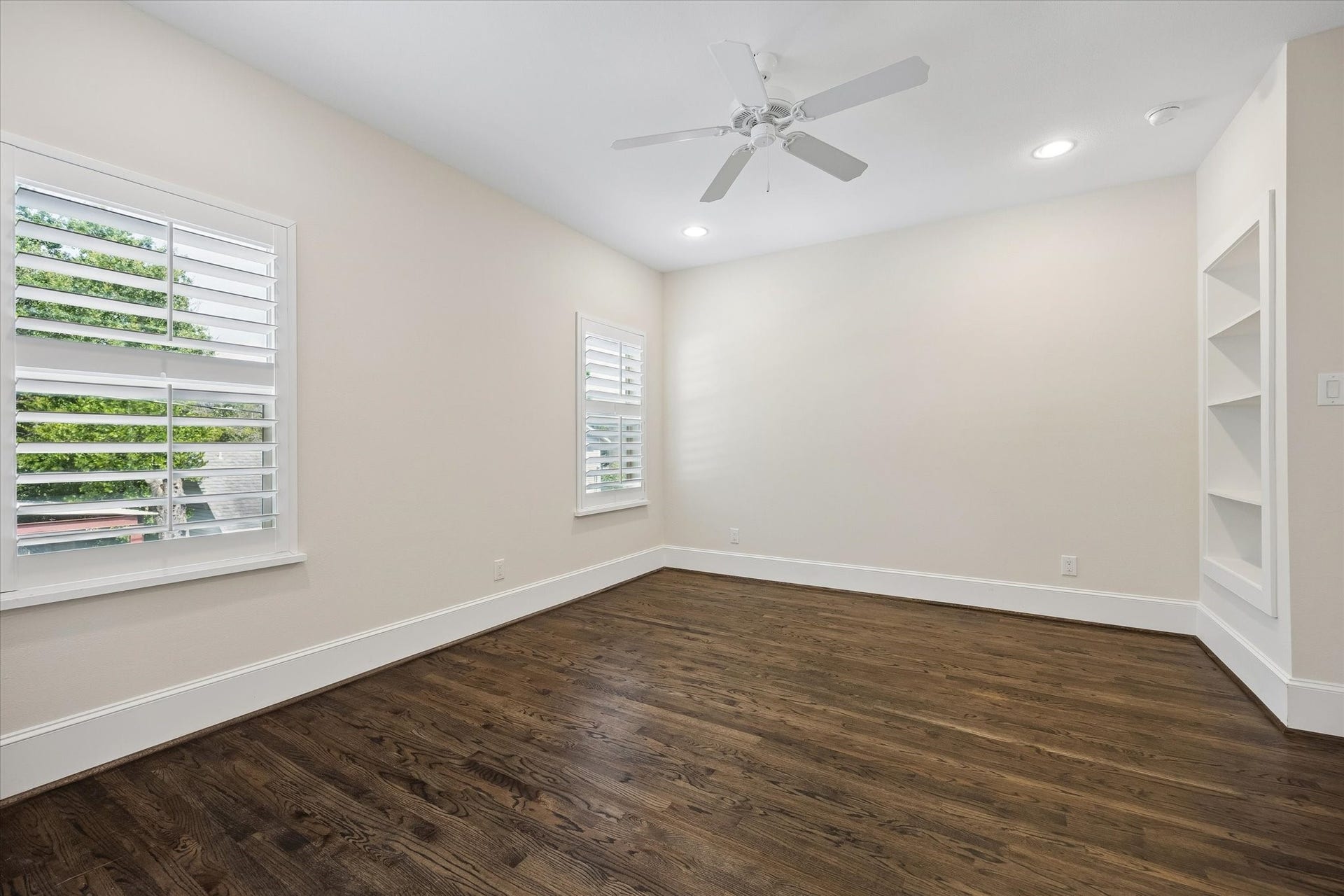 2111 Huldy Street, Houston, TX 77019 Secondary bedroom with hardwood floors, built-in shelves, ceiling fan, wood shutters, closet and access to a full bathroom.