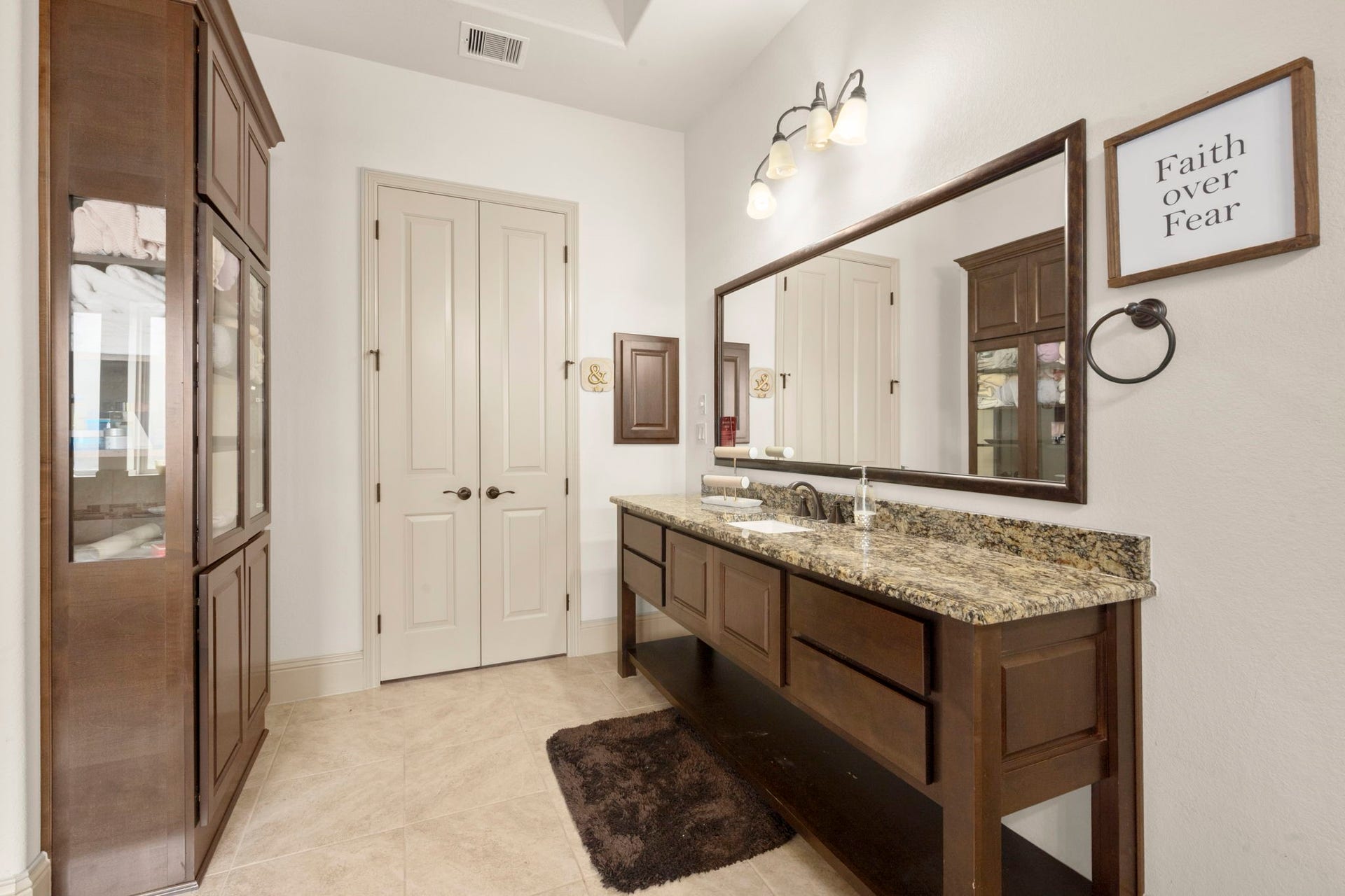 5103 Jackson Ponds Court, Sugar Land, TX 77479 This spacious bathroom features dual vanities with granite countertops, elegant lighting fixtures, and ample cabinet storage. It also features a shower, tub and two walk-in closets.