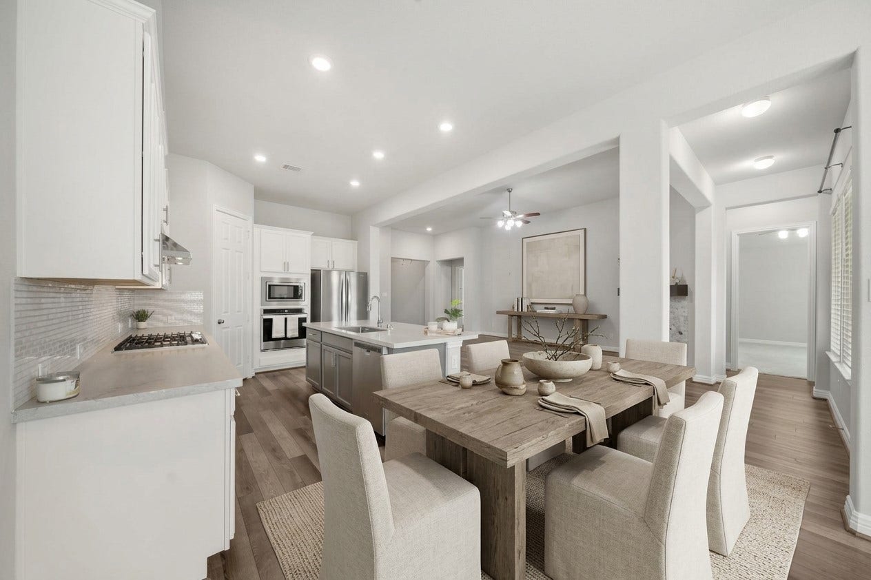 This wide-angle view captures the seamless flow between the kitchen and adjoining living areas. Rich wood-look flooring extends throughout the open floor plan, while recessed lighting, a generous island, stainless steel appliances, and abundant cabinetry create a bright, connected space perfectly suited for daily living and entertaining. This photo has been virtually staged for visual reference.