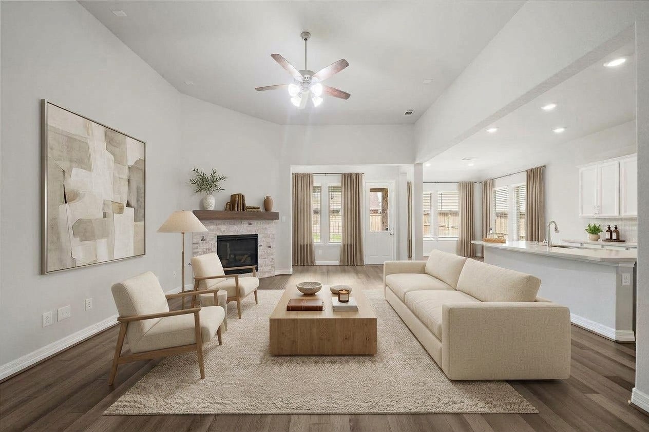 The open-concept living area offers an impressive combination of space, natural light, and effortless flow. A stone-accented fireplace creates a warm focal point, while expansive windows and high ceilings enhance the bright atmosphere. The adjoining kitchen and dining spaces make everyday living and entertaining feel seamless. This photo has been virtually staged for visual reference.