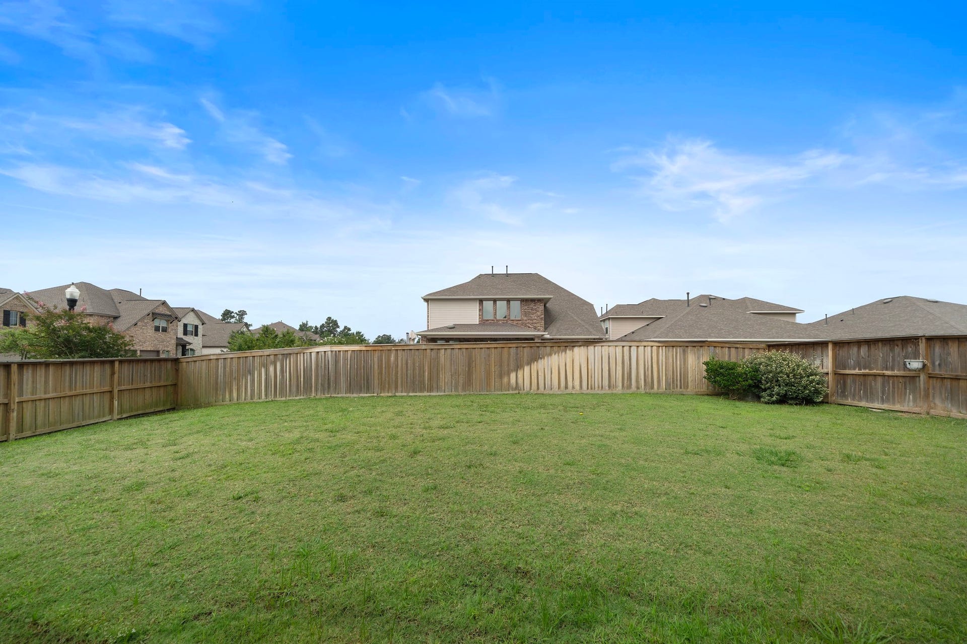 This spacious backyard provides an impressive amount of usable green space surrounded by wood privacy fencing. The broad lawn offers flexibility for entertaining, play, gardening, pets, or creating a personalized outdoor retreat, while neighboring homes and mature landscaping contribute to the established residential setting.
