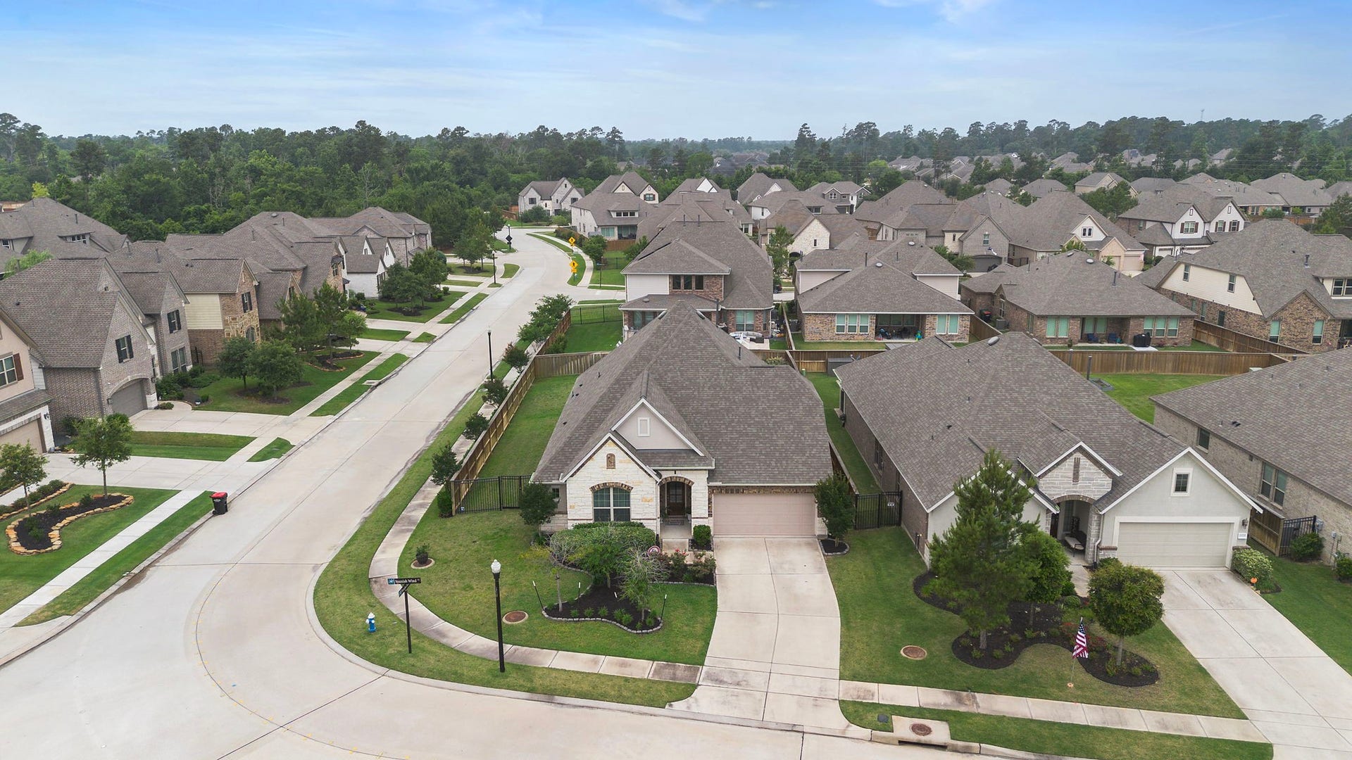 Drone images of an elevated aerial view highlights the homes appealing corner-style placement, landscaped front yard, wide driveway, and surrounding residential streets. The neighborhood features sidewalks, well-maintained homes, mature landscaping, and an attractive mix of architectural styles that create a polished community setting.