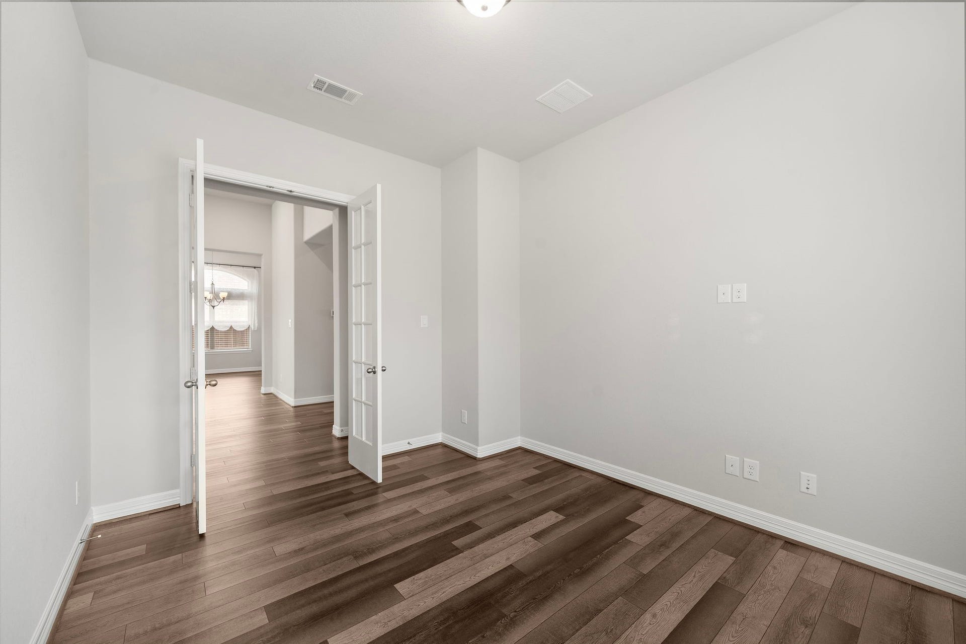 This versatile room features rich wood-look flooring, neutral finishes, and elegant French doors that create separation while maintaining an open, connected feel. With generous wall space and easy access to the adjoining living areas, it is well suited for a private office, study, library, media room, or flexible bonus space.