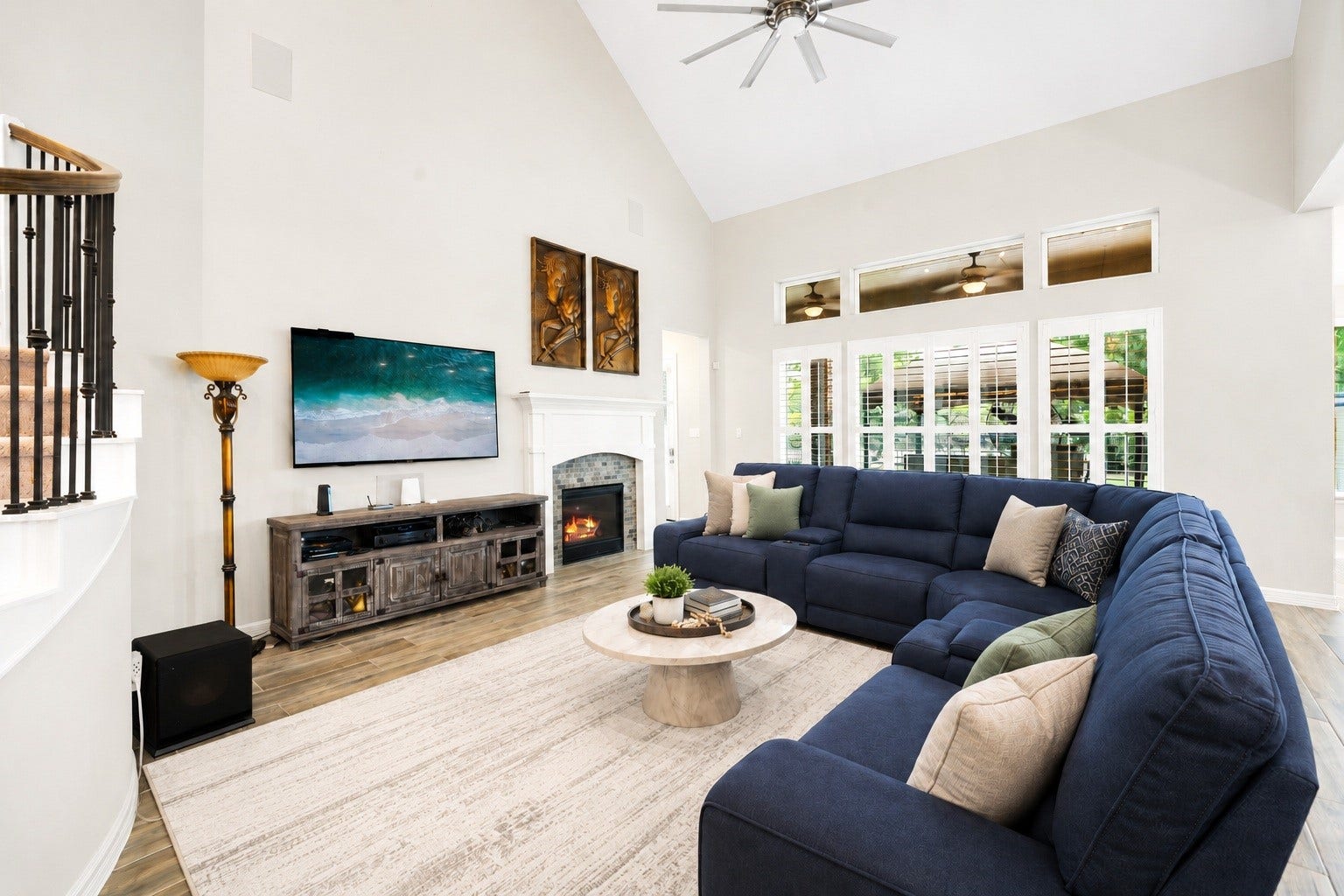 The living area offers a bright, open layout with vaulted ceilings, a gas log fireplace, and large shuttered windows overlooking the backyard. Virtually staged.