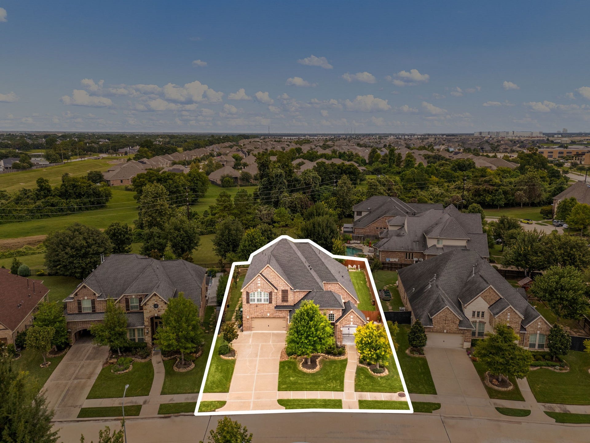 An aerial perspective highlighting the home's size and setting within Harvest Green, framed by mature landscaping and neighboring homes.