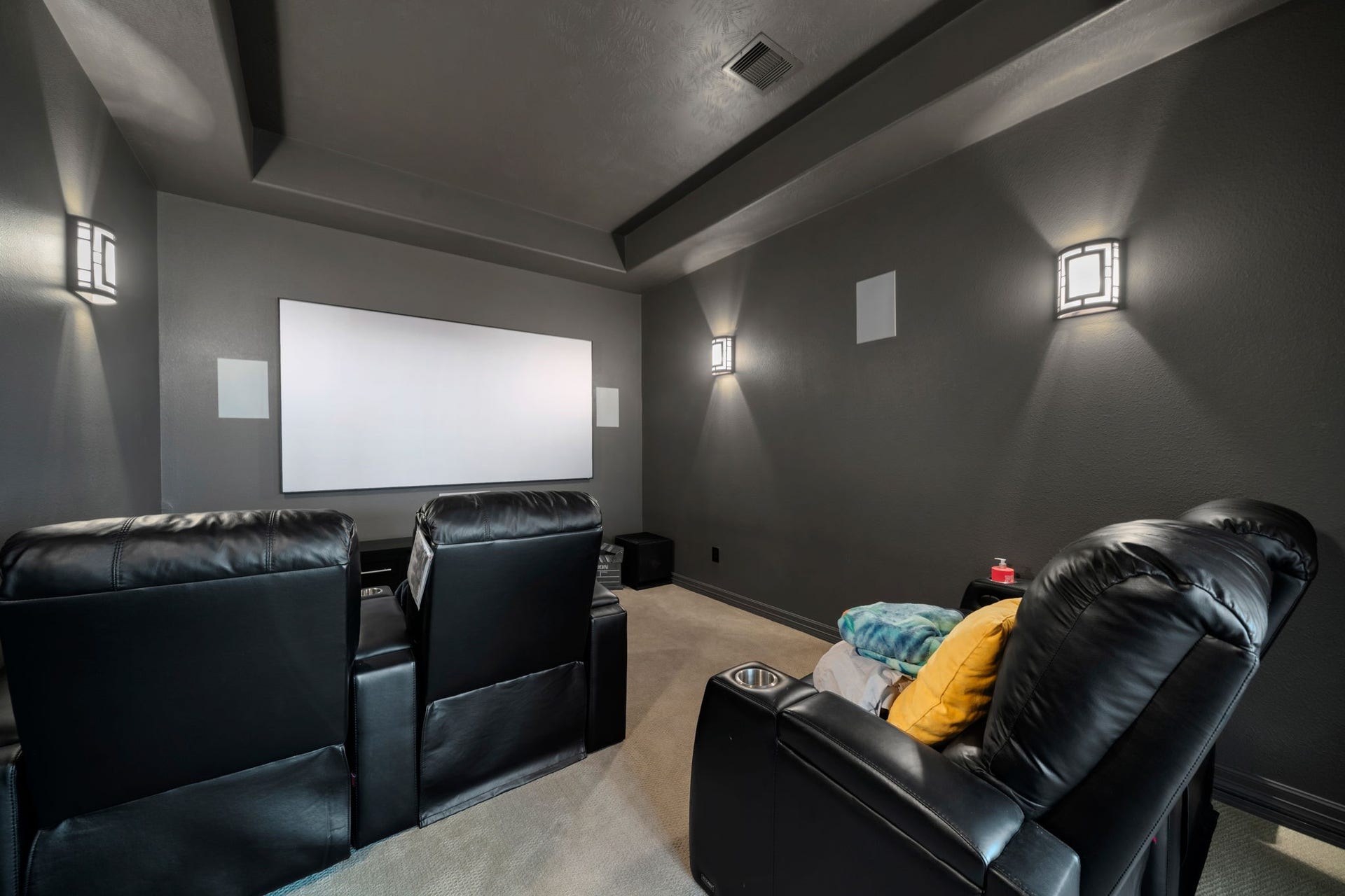 The dedicated media room sets the stage for movie nights, featuring tiered theater seating and a large projection screen.