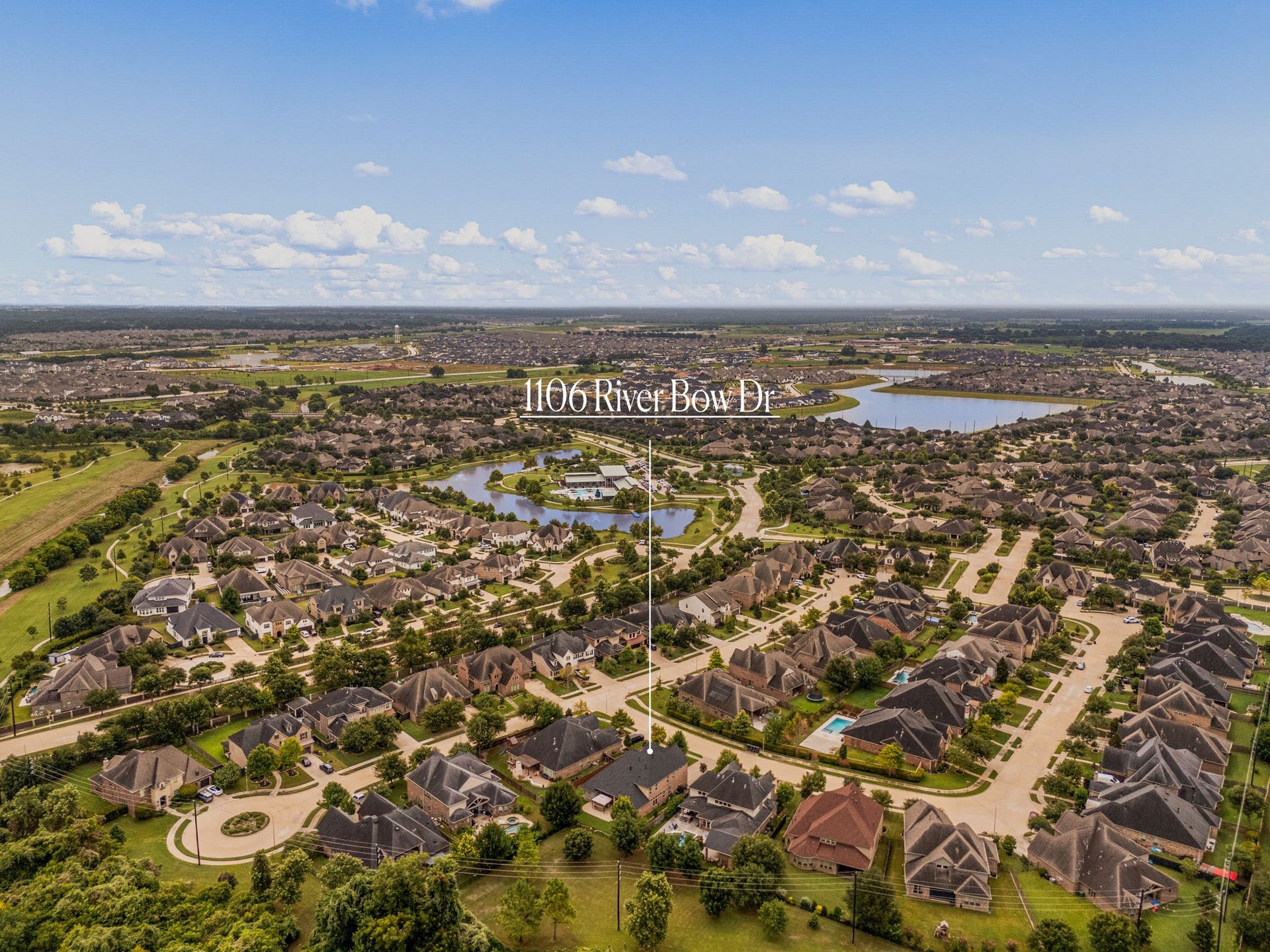 An aerial perspective highlighting the home's setting within Harvest Green, surrounded by tree-lined streets, a neighborhood lake, and easy access to community green space.