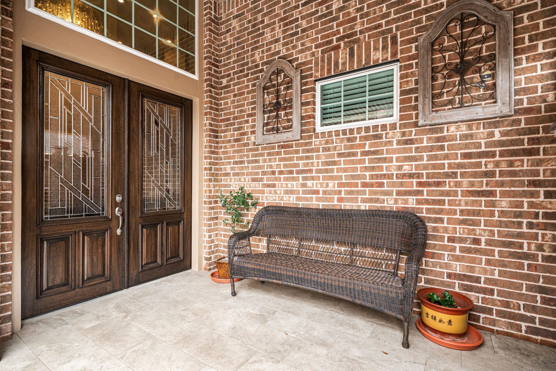 A covered entry welcomes you home, featuring double glass-paneled doors and a tiled front porch overlooking the landscaped front yard.