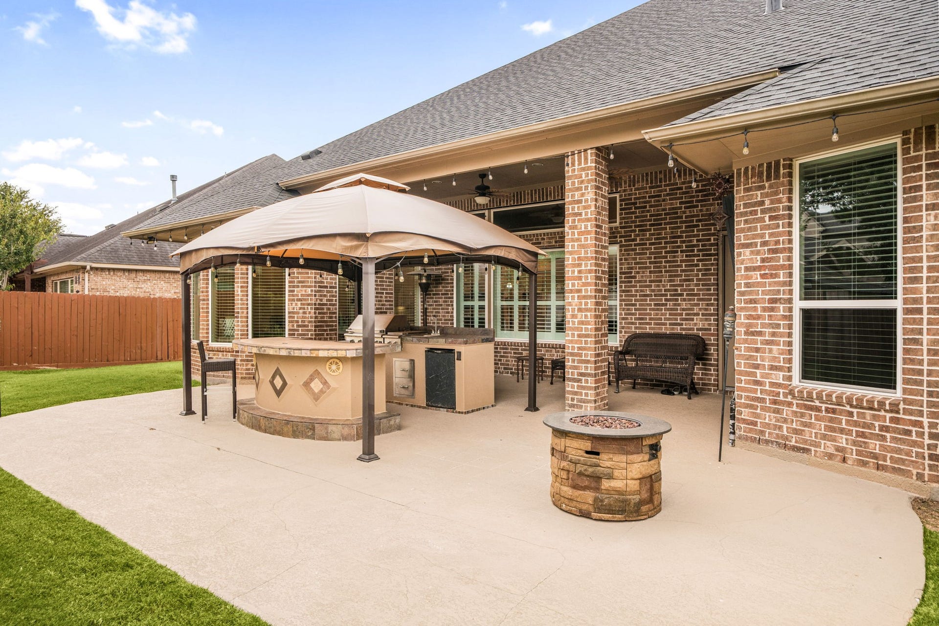 The custom outdoor kitchen features a built-in grill, sink, and covered seating area  perfect for hosting year-round.