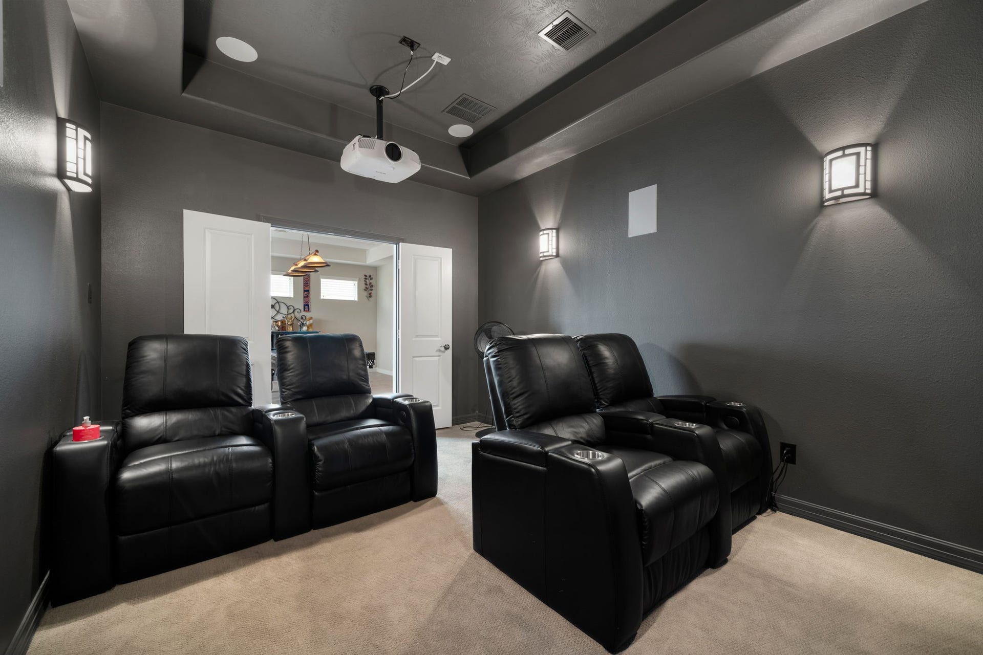 A closer look at the media room, complete with theater-style reclining seats and ambient wall lighting for an immersive viewing experience.