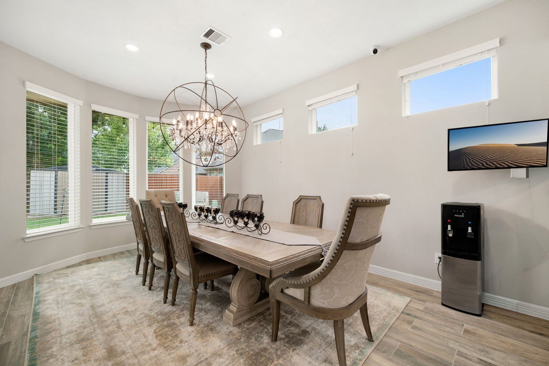 A sunlit dining area offers a curved wall of windows and a statement chandelier, creating an elegant setting for everyday meals or entertaining.