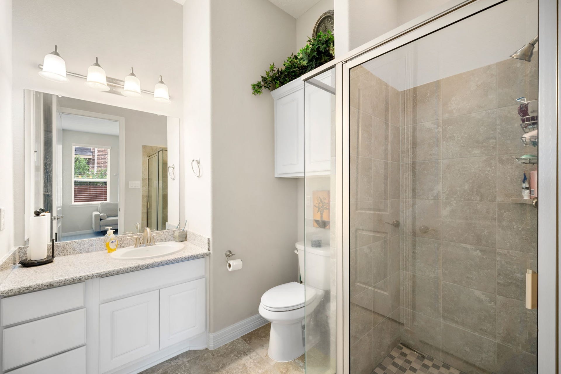 A secondary bathroom features a granite-topped vanity and a walk-in glass shower, offering convenient access for guests or family.