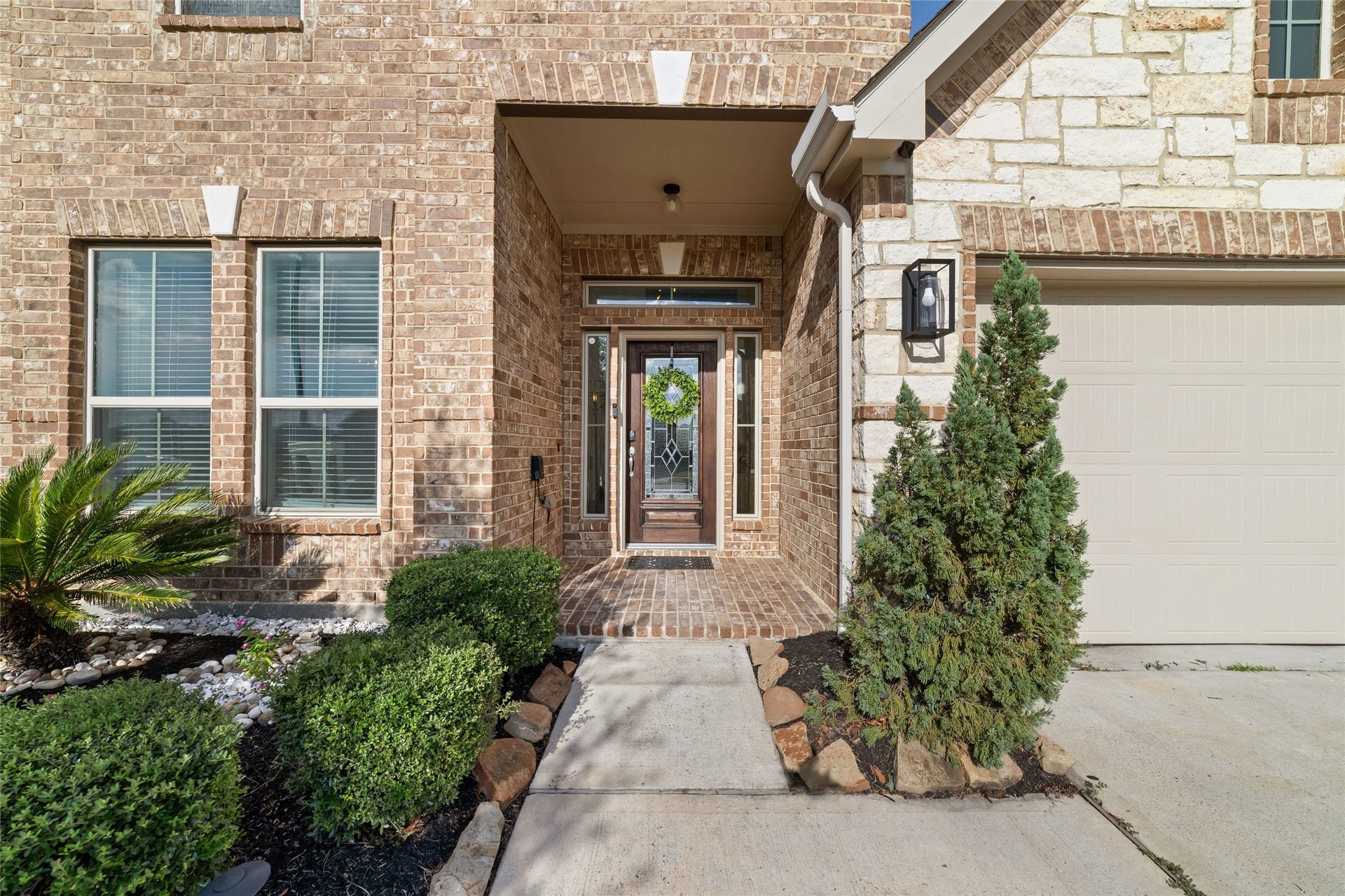 Charming covered front entry with brick detailing and established landscaping.