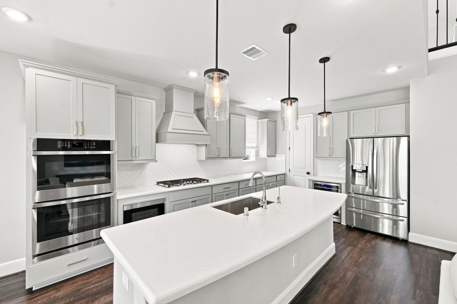 3011 Lantana Trail, Katy, TX 77493 The open-concept kitchen features quartz countertops, oversized island, double ovens, microwave drawer and remote Roman shades. Walk in pantry is accessible through the door in the corner.