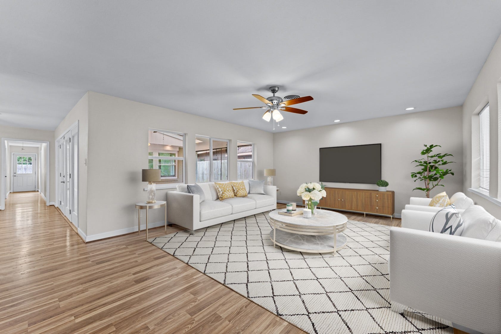 This spacious front living room features a wall of windows that provide a view of the covered patio. Virtually staged photo.