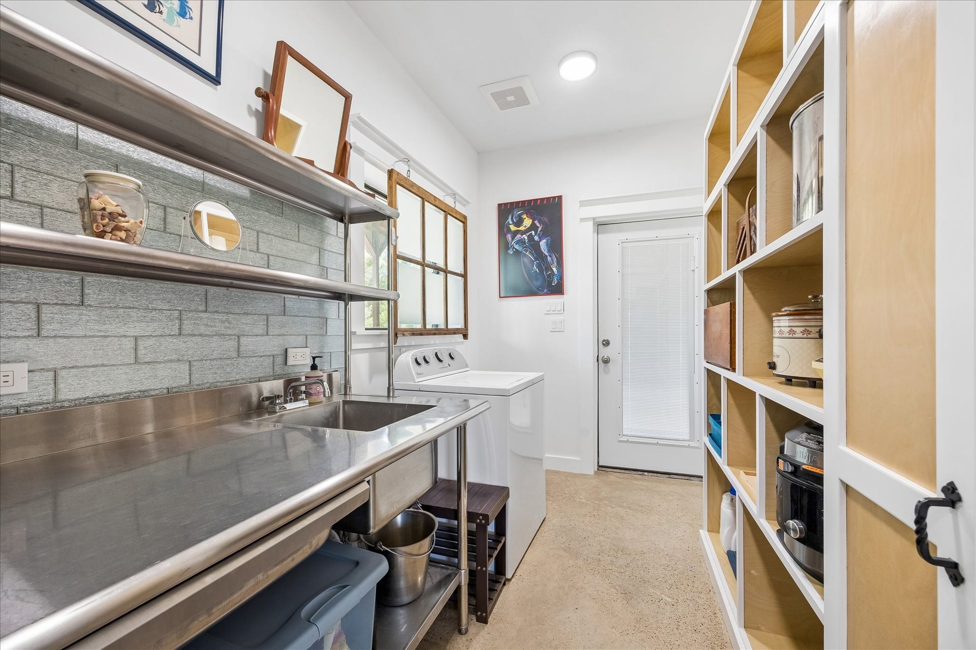 33 Riverwood Lane, Hempstead, TX 77445 Laundry room with a commercial-grade stainless steel worktable, sink, shelving, washer and dryer connections and built-in storage on the opposite wall.