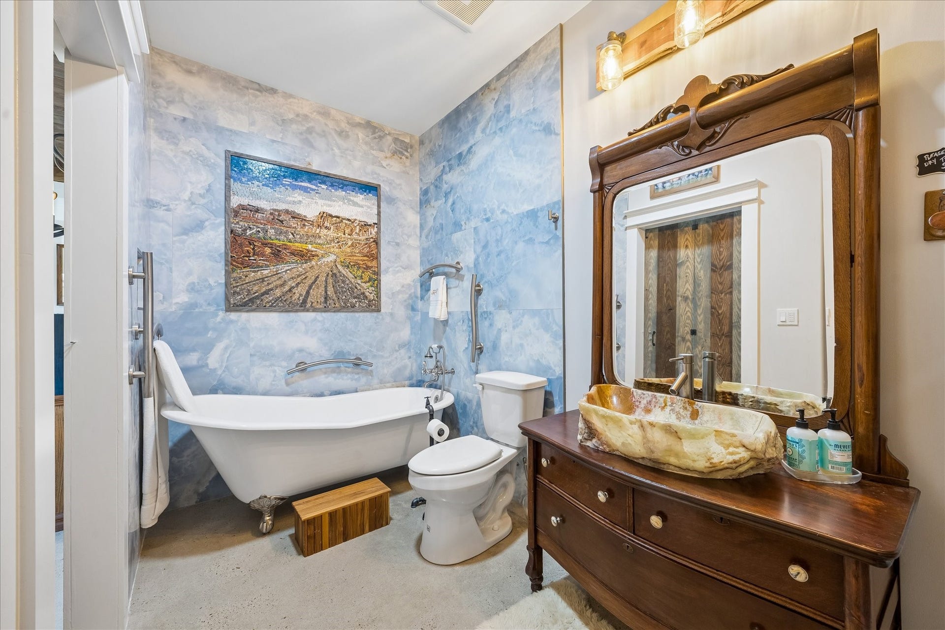 33 Riverwood Lane, Hempstead, TX 77445 Full bath adjoining the living area features an antique dressing cabinet repurposed with a natural stone sink, floor-to-ceiling sky-blue tile surrounding the clawfoot tub, and a large mosaic tile mural that brings a sense of calm to the space.