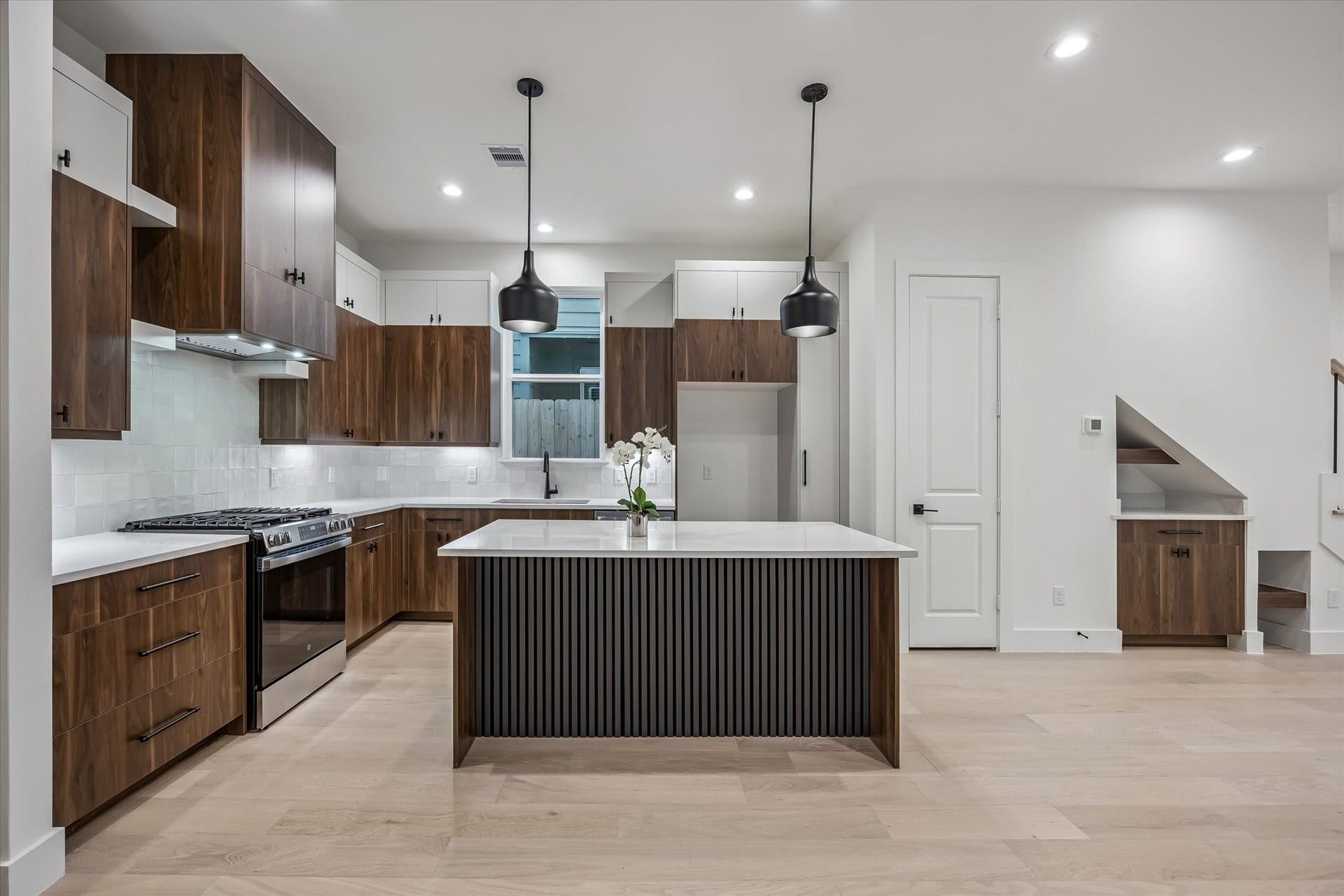 Modern kitchen featuring elegant wood cabinetry, a central island with sleek pendant lighting, and stainless steel appliances, offering both style and functionality.