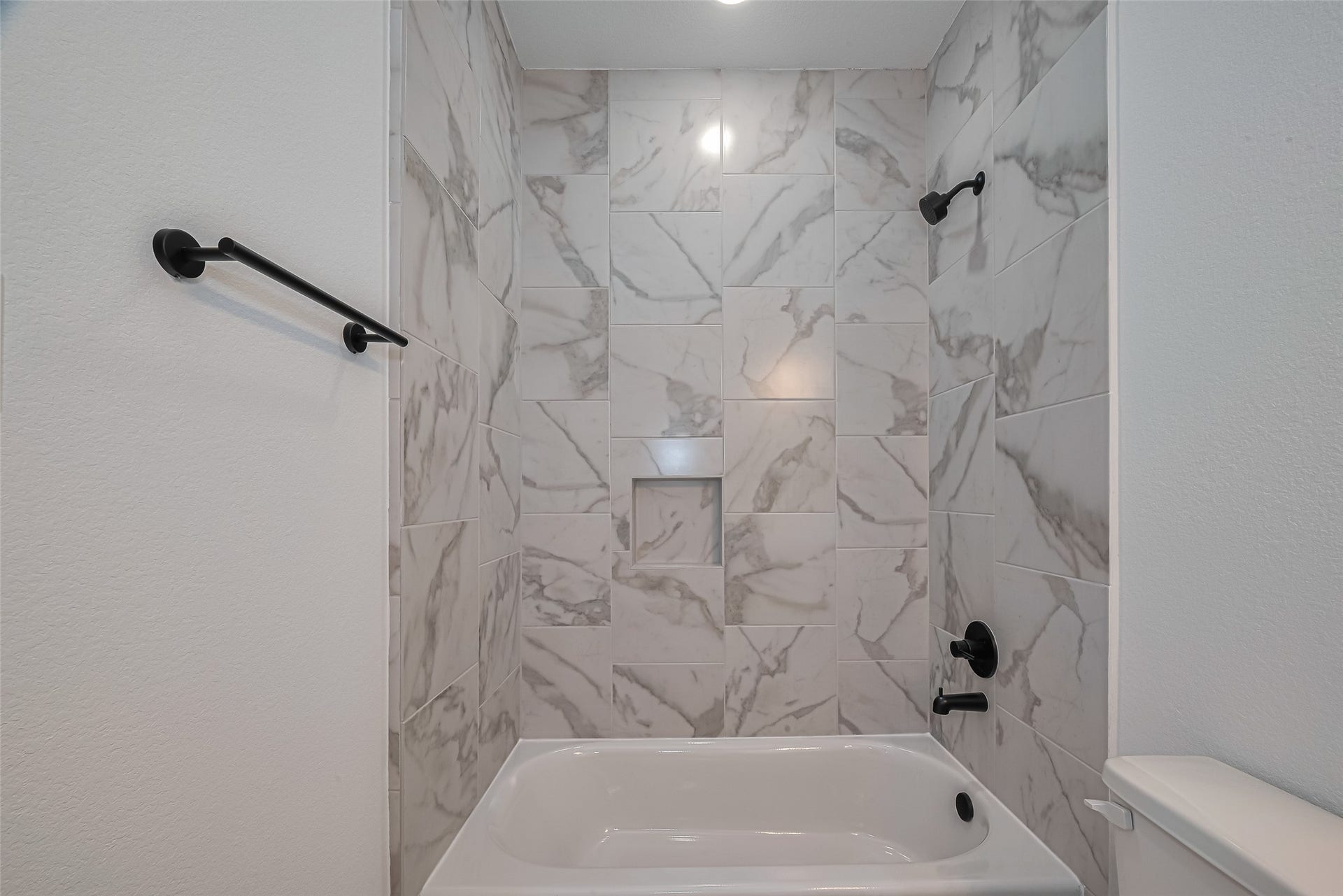 1350 W 24th Street, Houston, TX 77008 Bathroom featuring a tub and shower combination with beautiful marble-look tile.