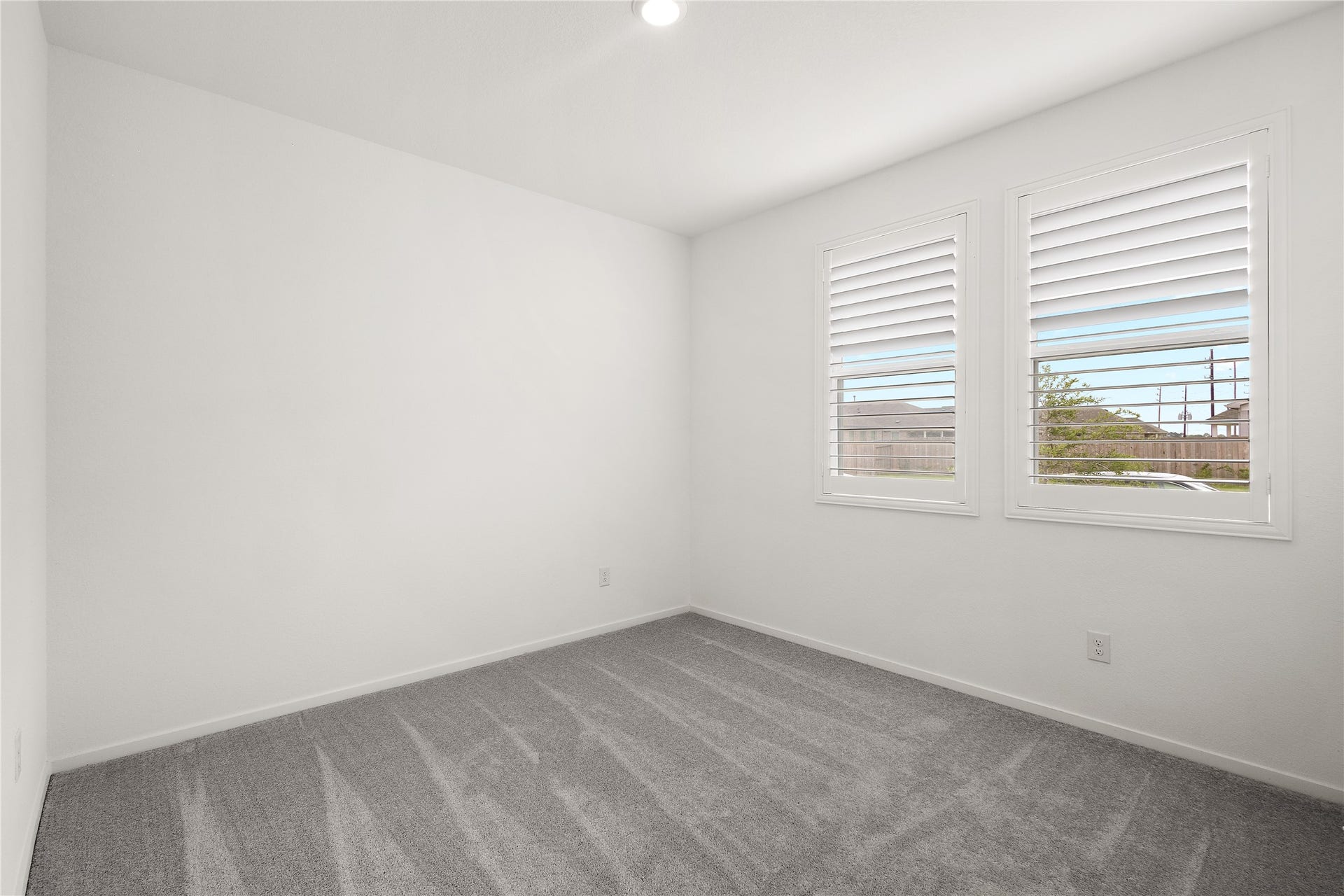 3414 Eden Valley Lane, Rosenberg, TX 77471 This bright room features clean white walls and soft gray carpeting. Two windows with shutters provide natural light and a view outside, creating an inviting and versatile space.